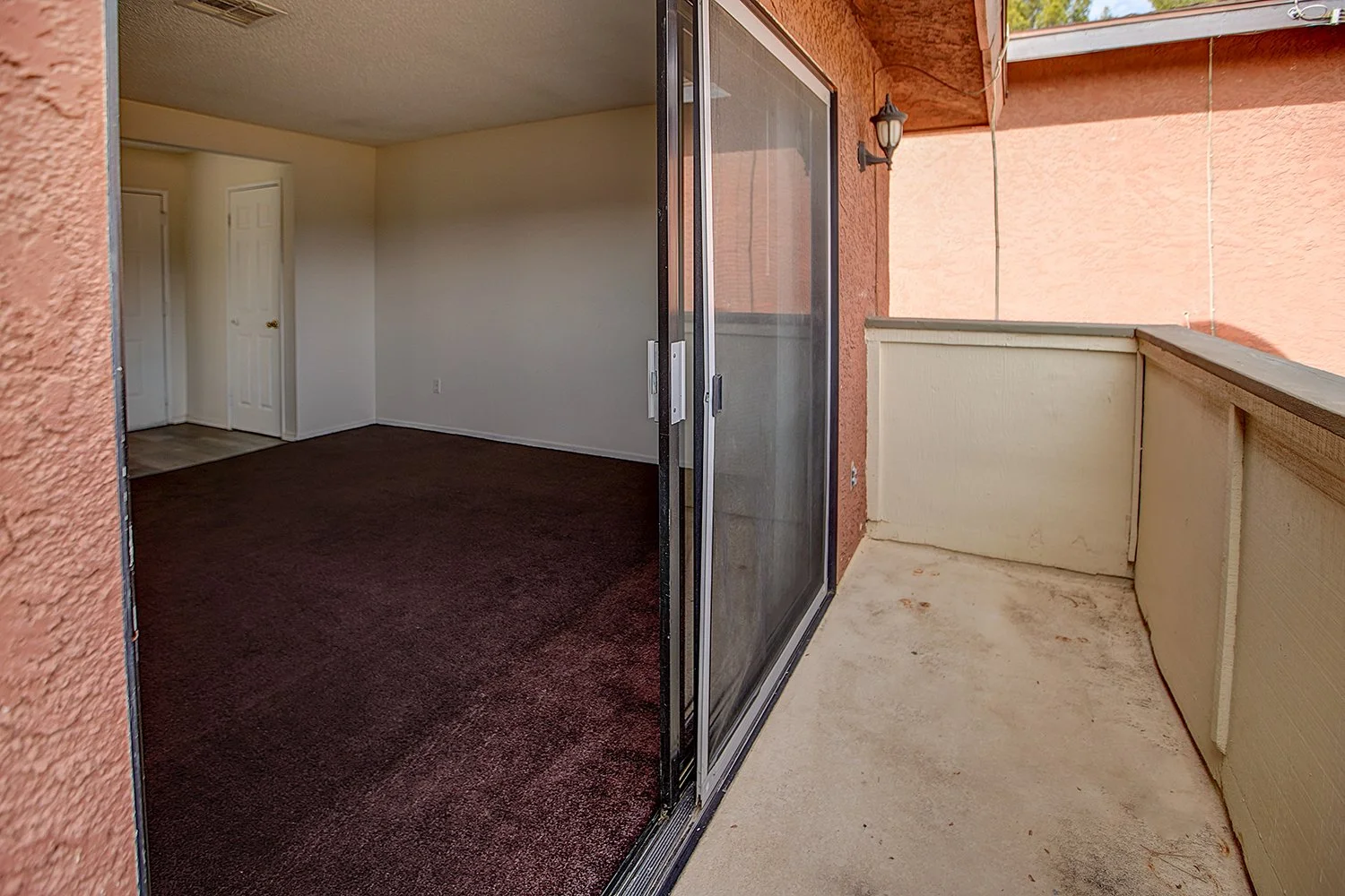 This image is a split look into the living room and the connected balcony, seperated by a sliding glass door and railing.