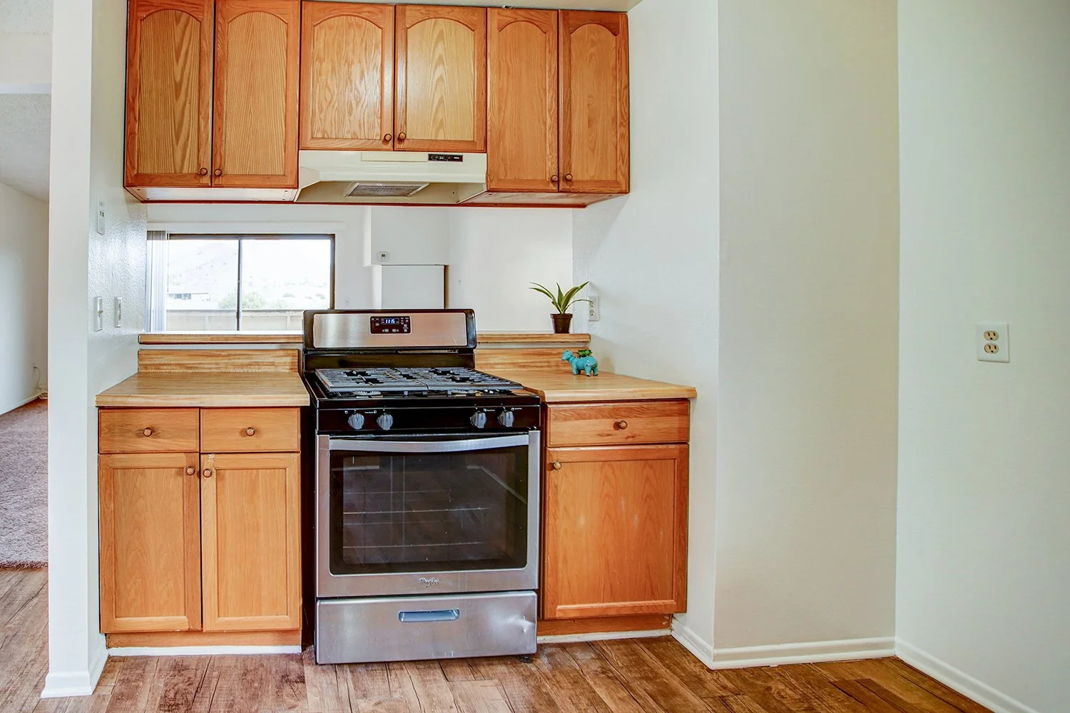 This image shows a look into the kitchen with wood cabinets and a black and silver stove.
