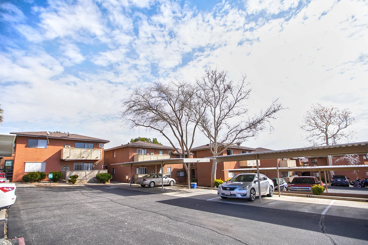 This image shows the parking structure with awnings to cover the vehicles, with the building in the background and trees.