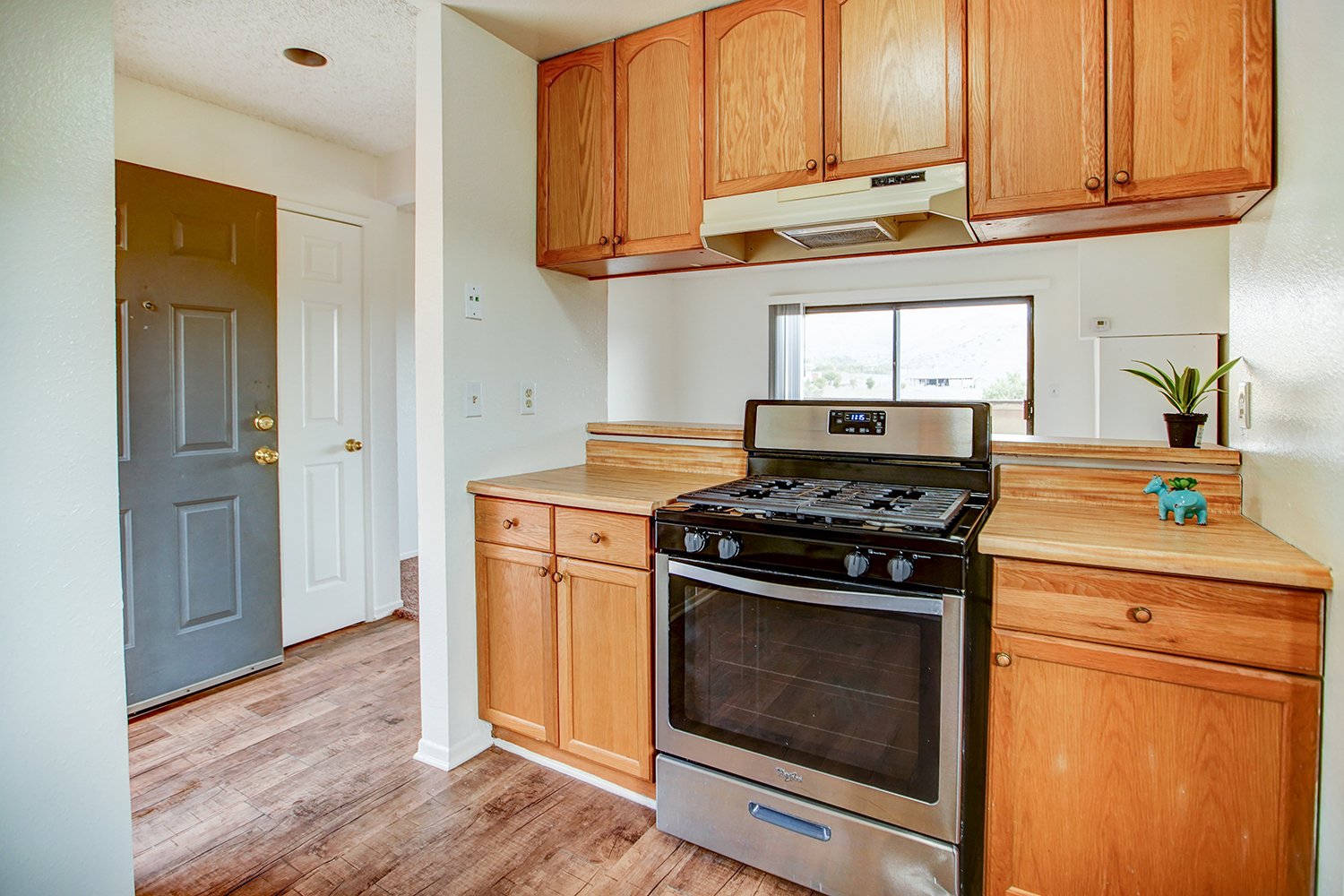 This image shows a look into the kitchen with wood cabinets and a black and silver stove.