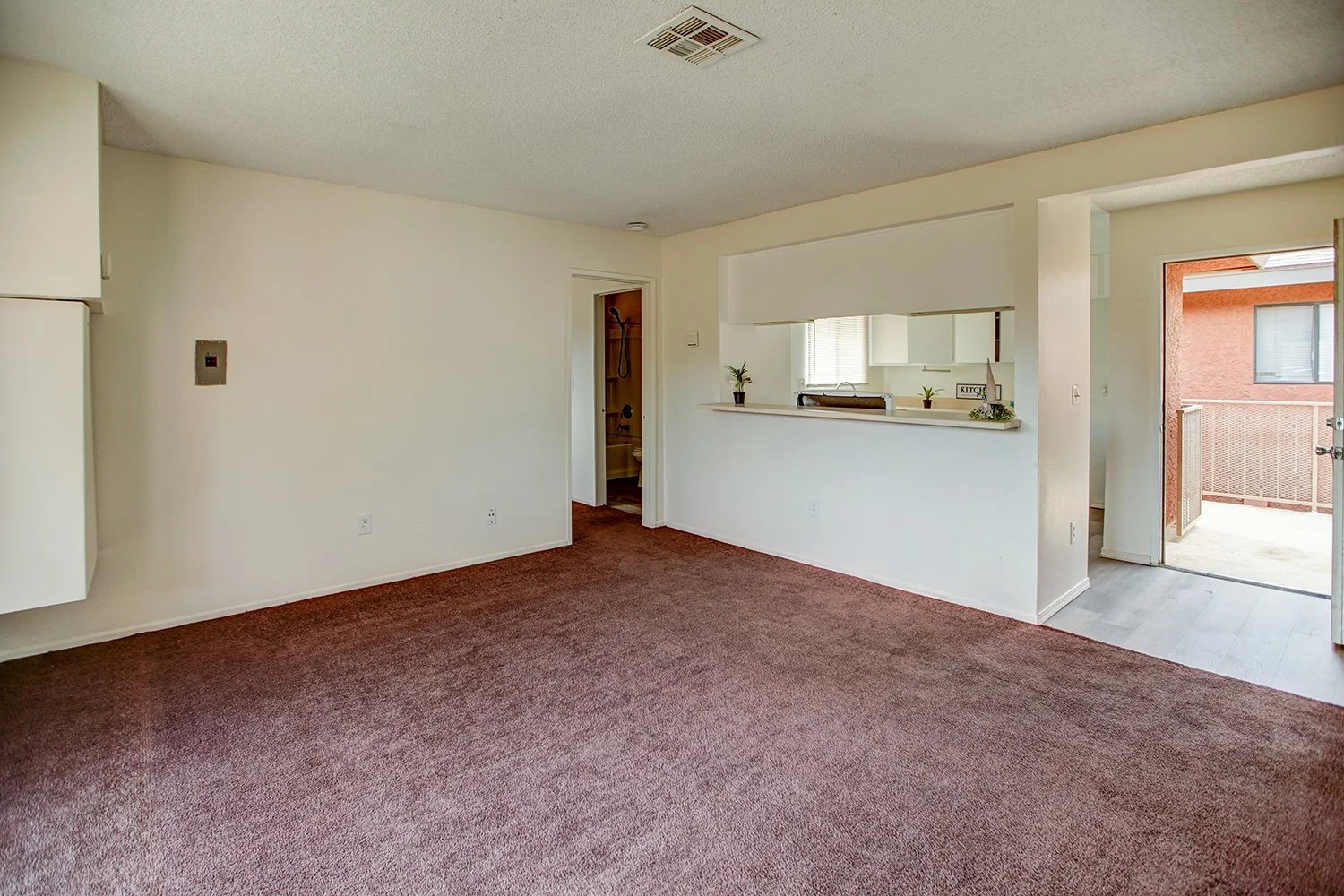 This image shows the carpeted living room and wood-floored kitchen. 
