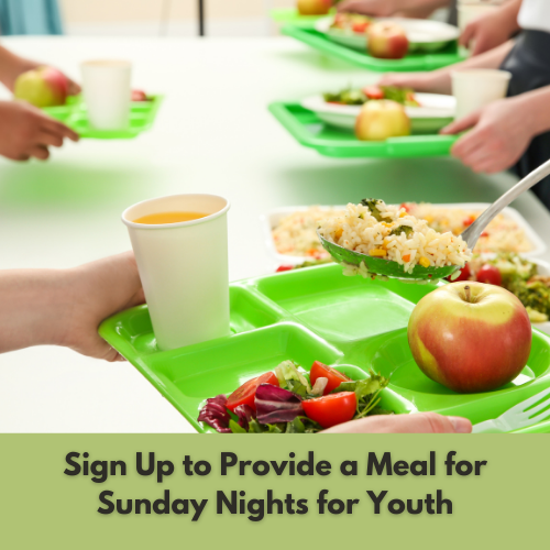Students in a cafeteria standing in line with green trays filled with food such as apples, salad, rice, and drinks, with a sign encouraging sign-ups for youth Sunday night meals.