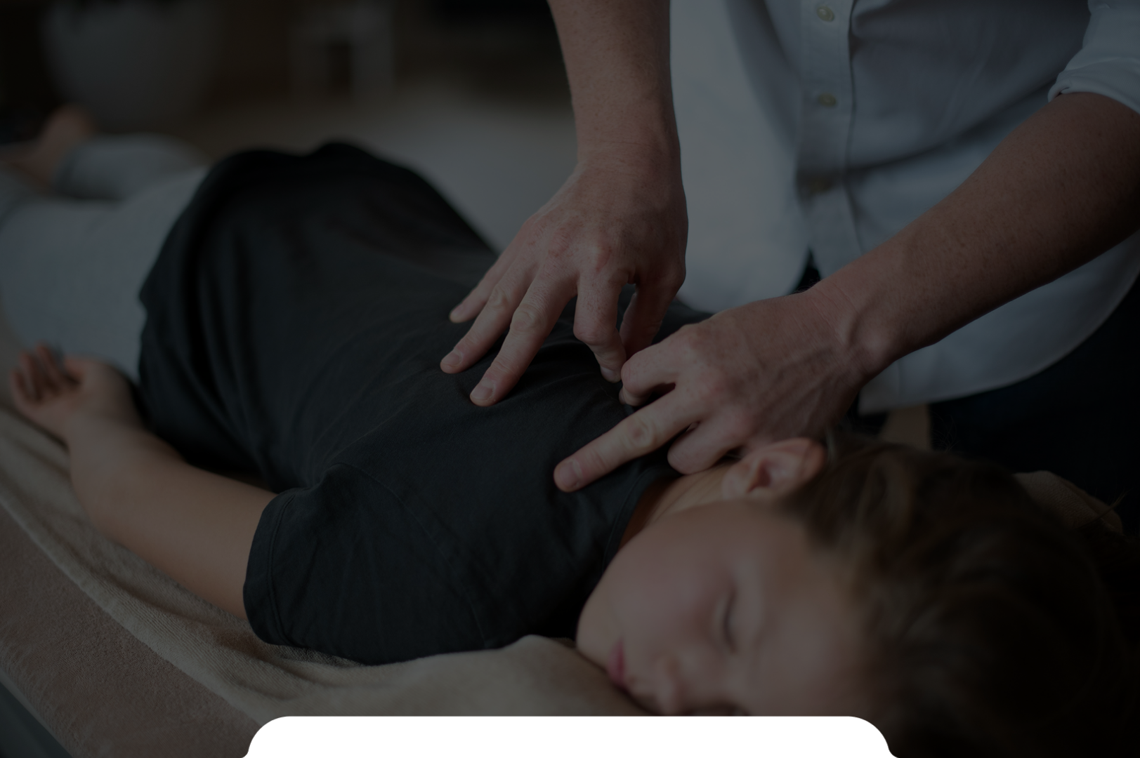 A person performing CPR on a woman lying face down on a medical table or massage table.