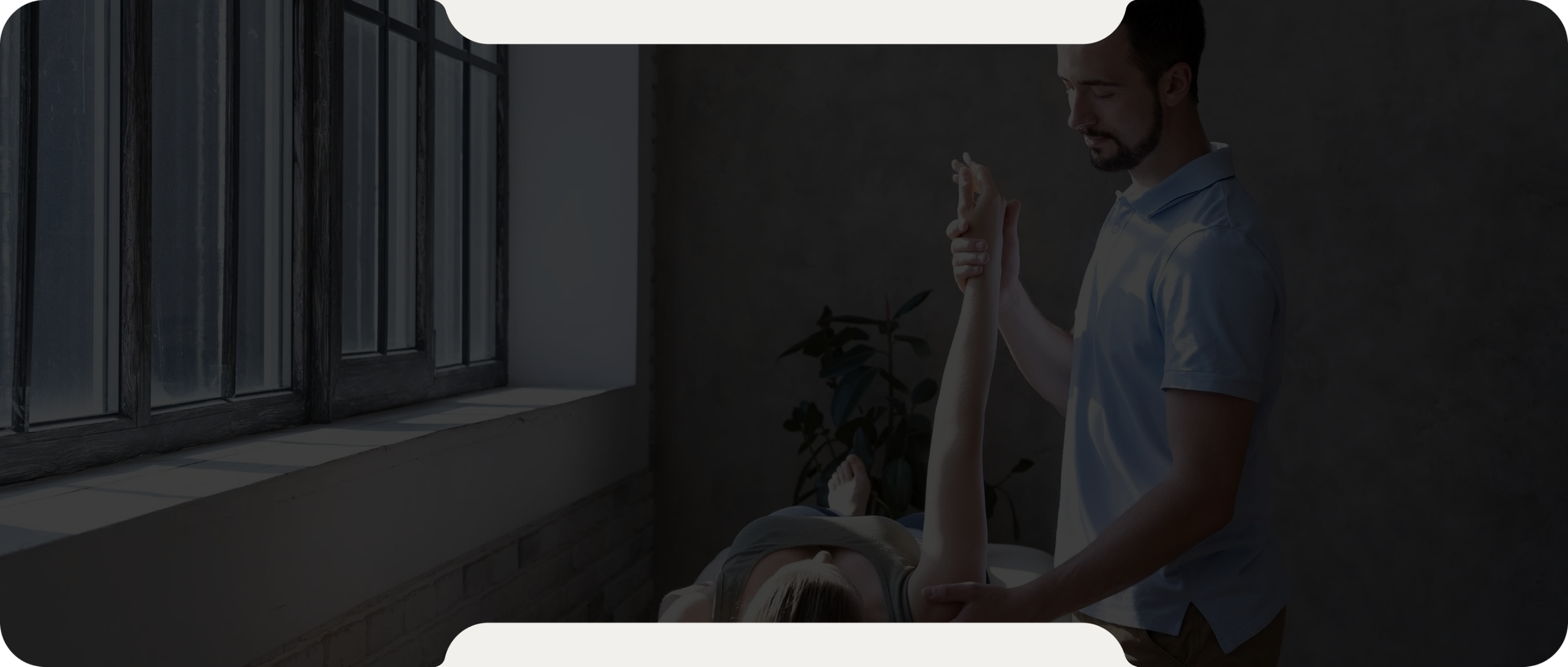 Physical therapist performing arm exercises on a woman lying on a treatment table in a clinic with large windows.