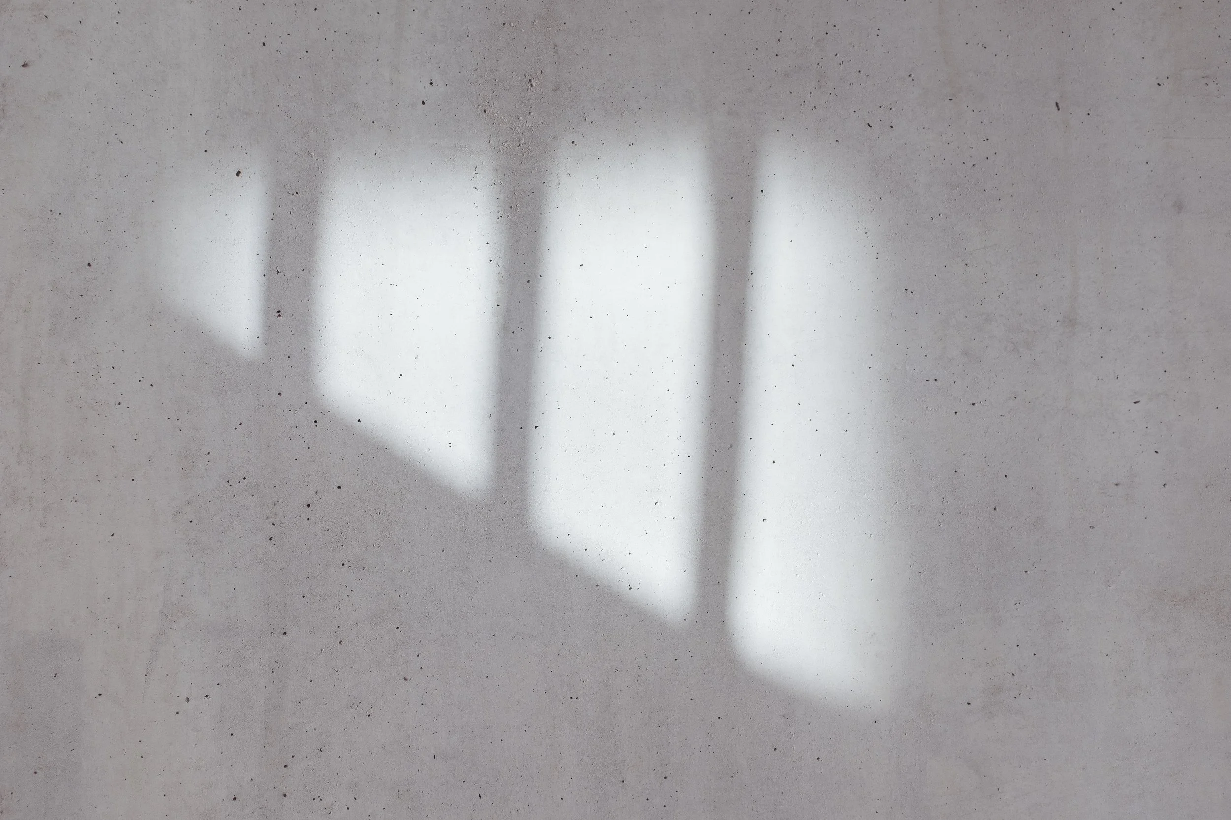 Shadow of a heart shape projected onto a concrete wall.