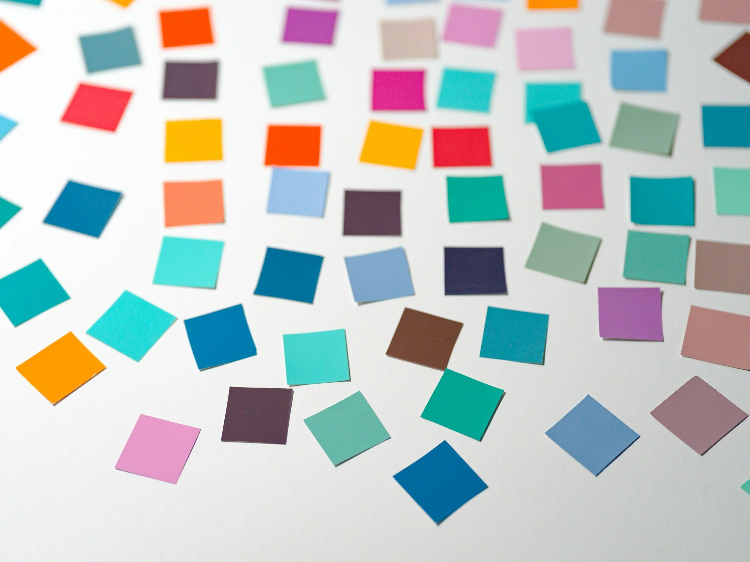 A collection of colorful square stickers scattered on a white surface.