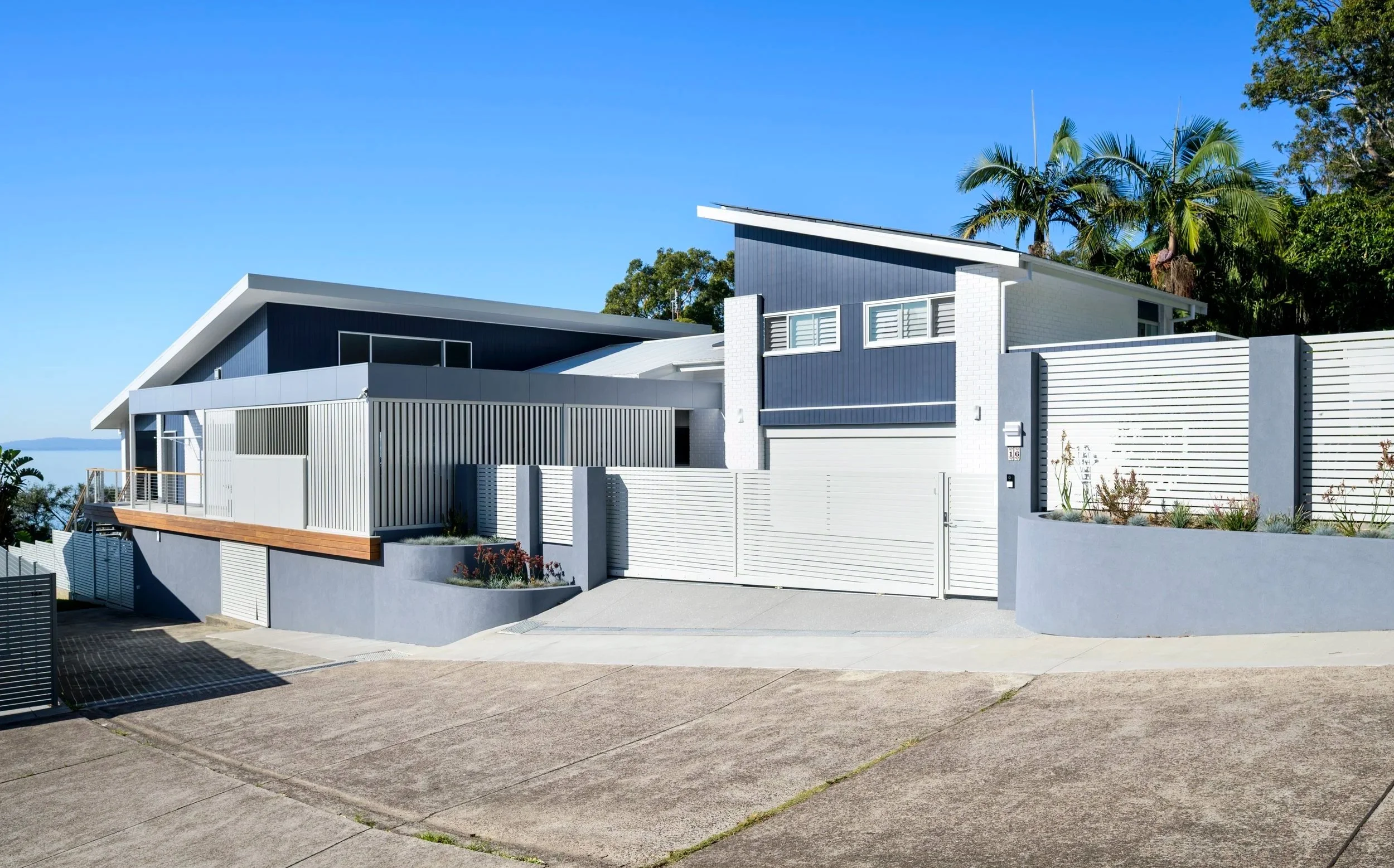 Modern kitchen with deep teal coved cabinetry, wooden accents, bar stools, and large island counter.