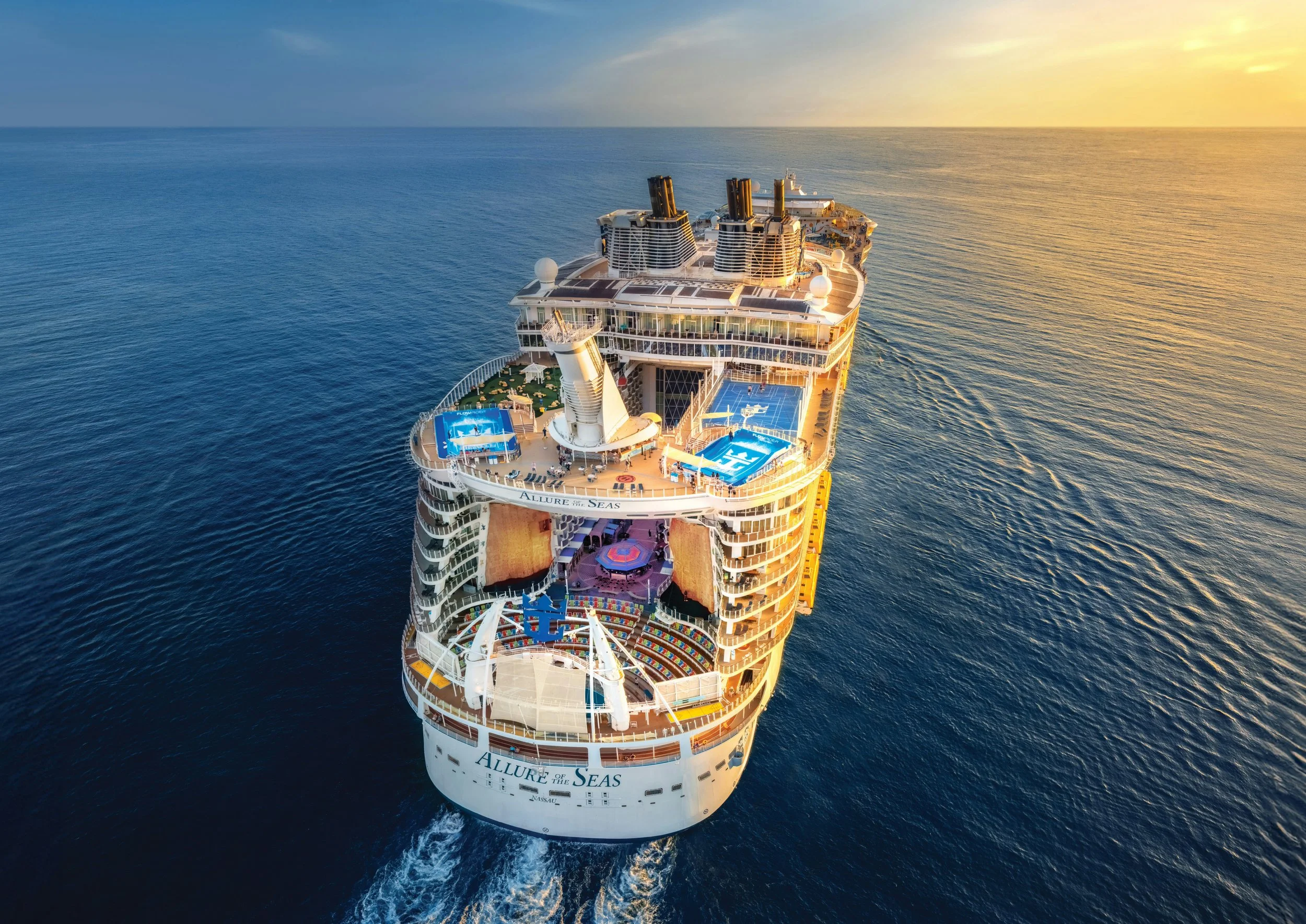 A large cruise ship named Allure of the Seas sailing on the ocean during sunset.