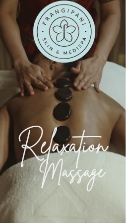 A person receiving a hot stone massage at a spa, with hot stones placed along their back. The spa offers skin and medspa services, promoting relaxation.