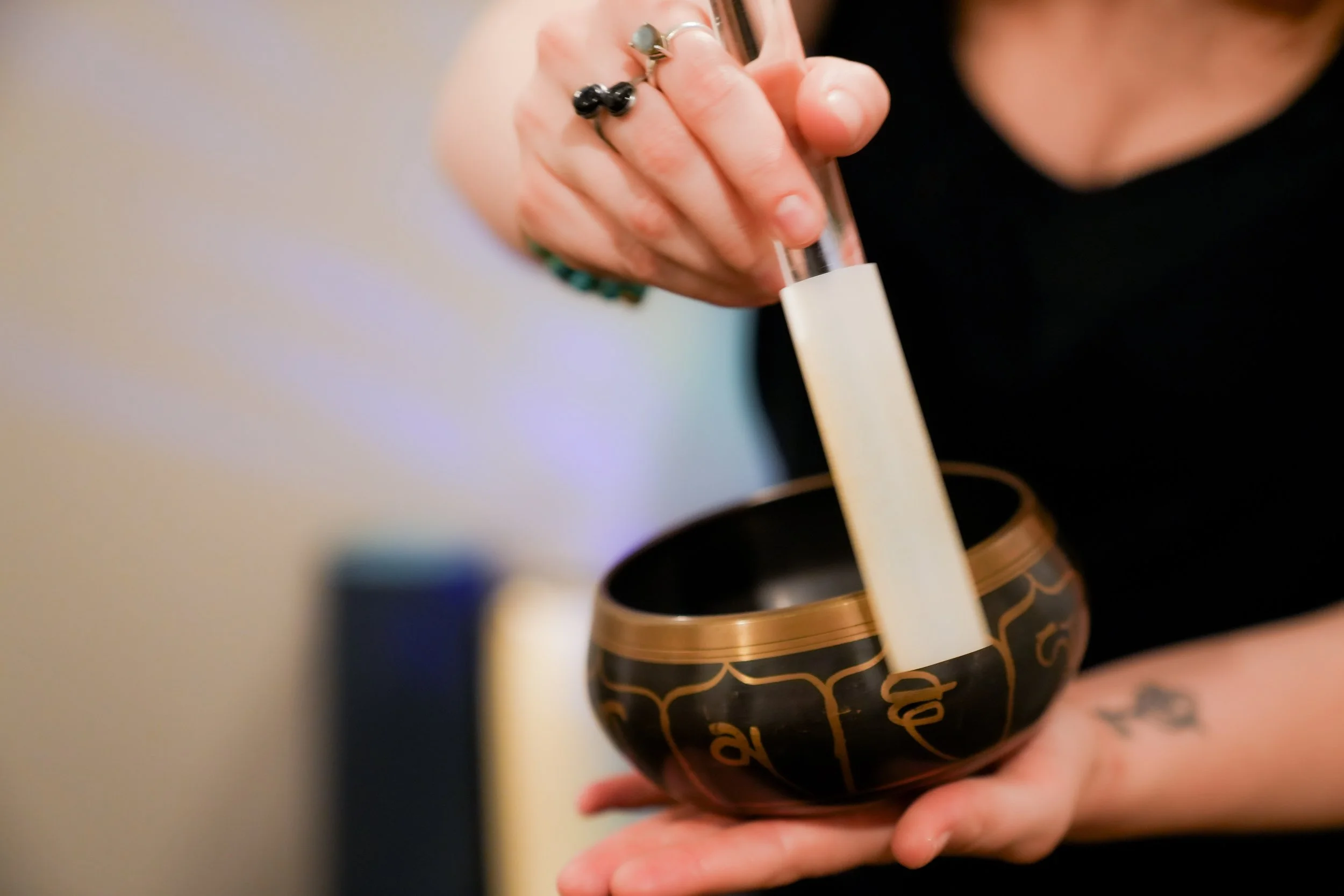 Maren holding and playing a Tibetan sound bowl, her face unpictured.