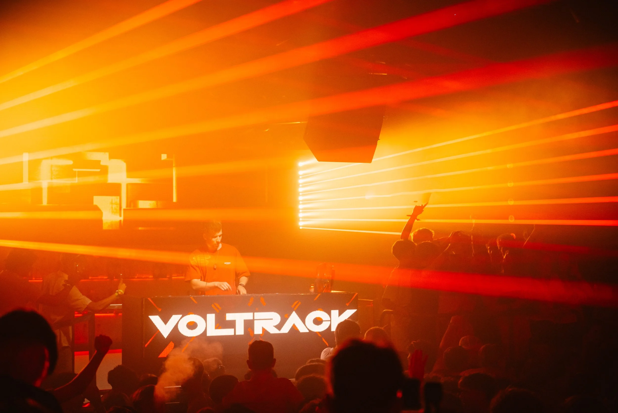 DJ performing at a club with bright orange and red lights