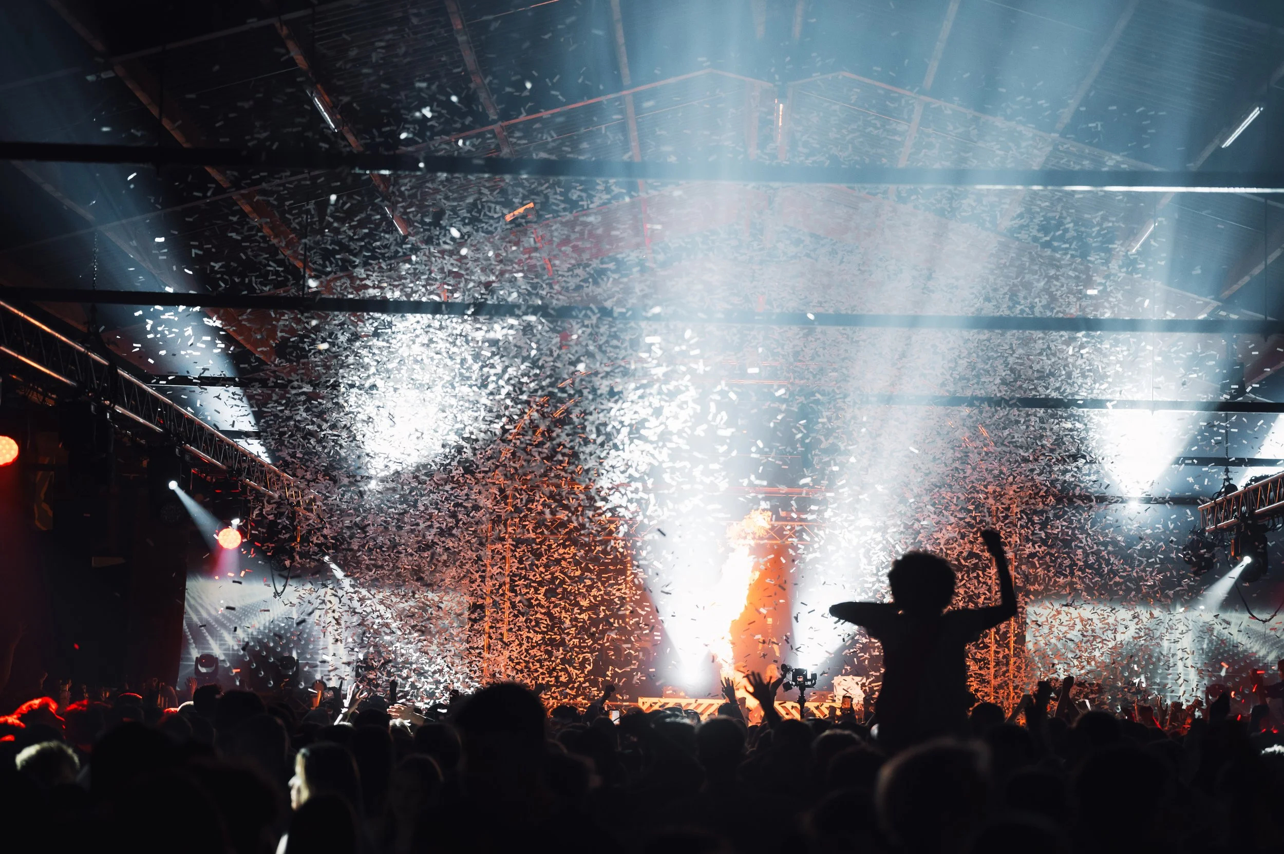 Concert scene with confetti and audience silhouettes under bright stage lights.