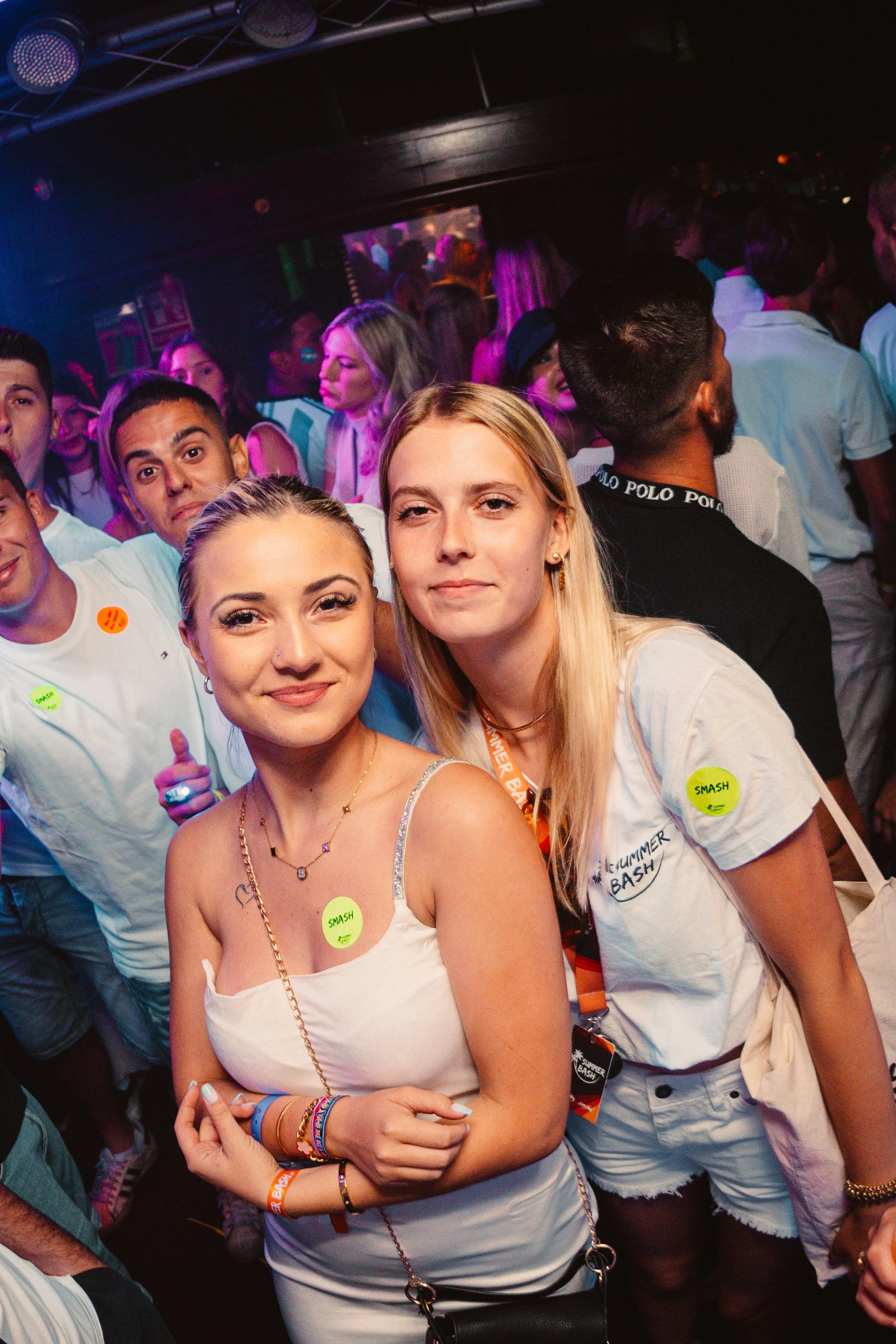 People enjoying a party with colorful lights and crowd.