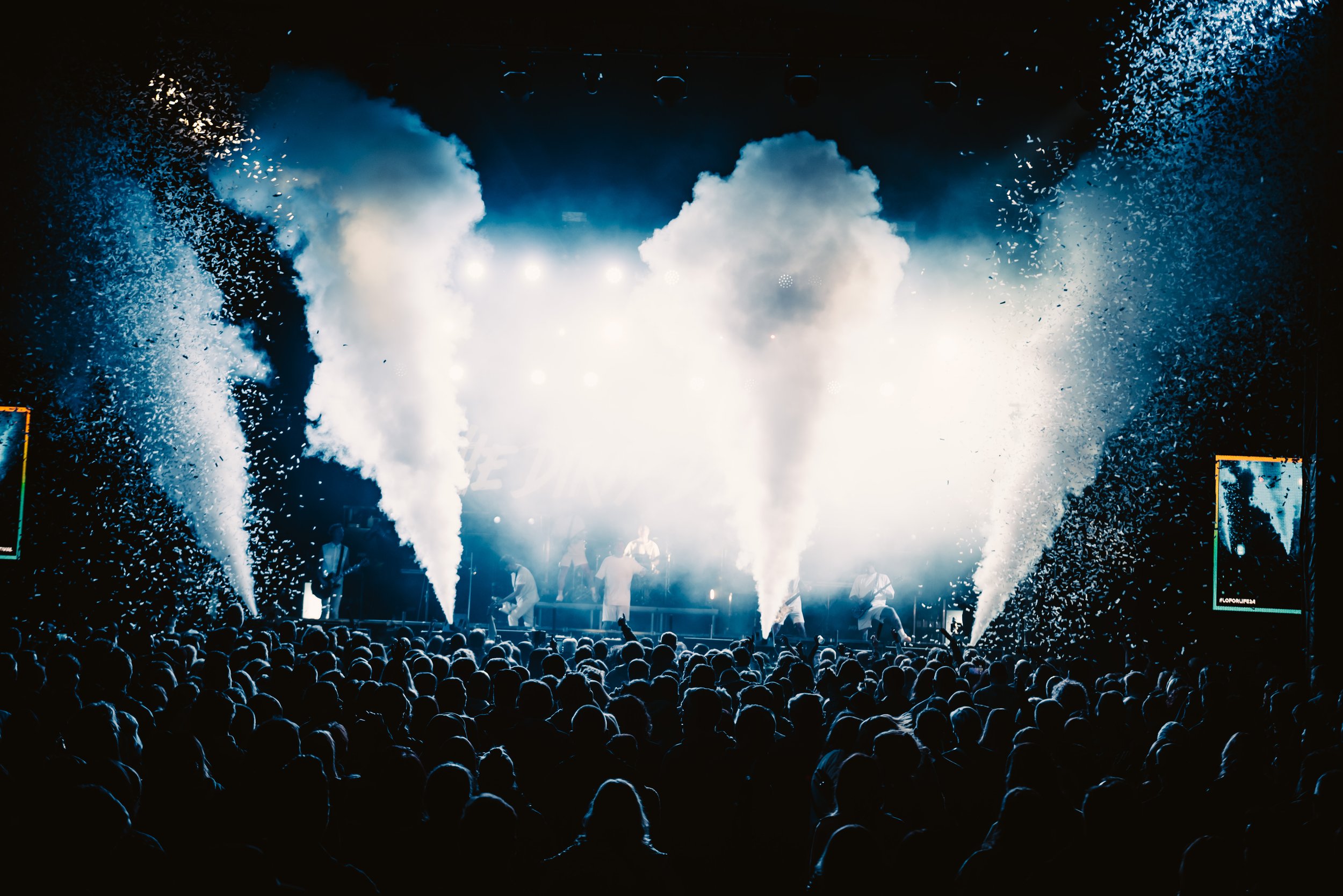 Concert with a crowd, stage lighting, and smoke effects.