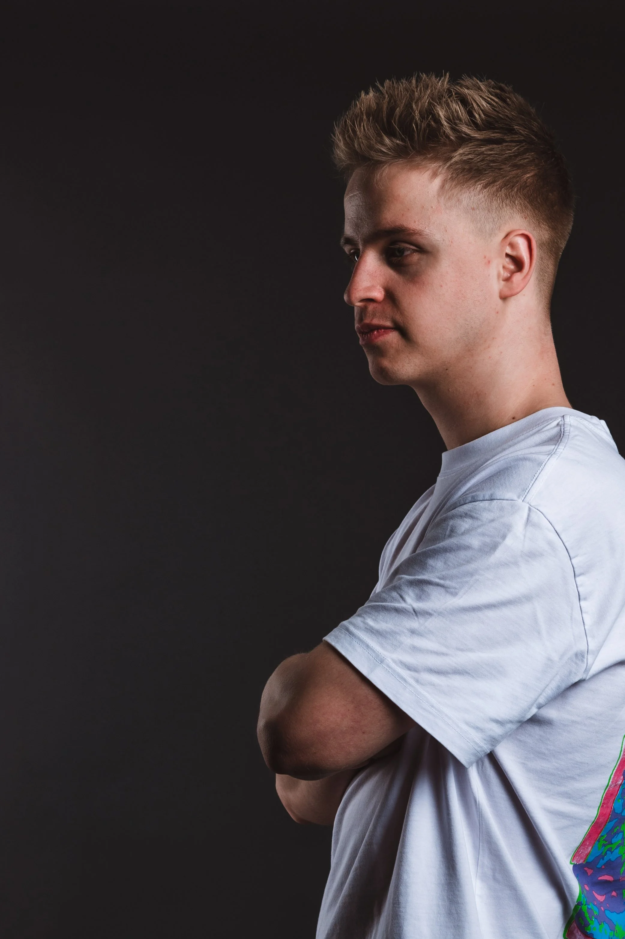 Side profile of a person in a white t-shirt against a dark background.