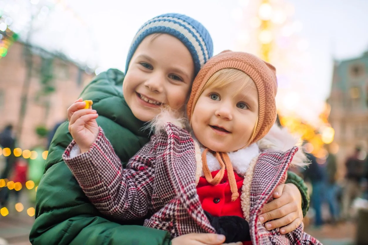 Siblings sharing a cuddle, outdoors in winter clothes