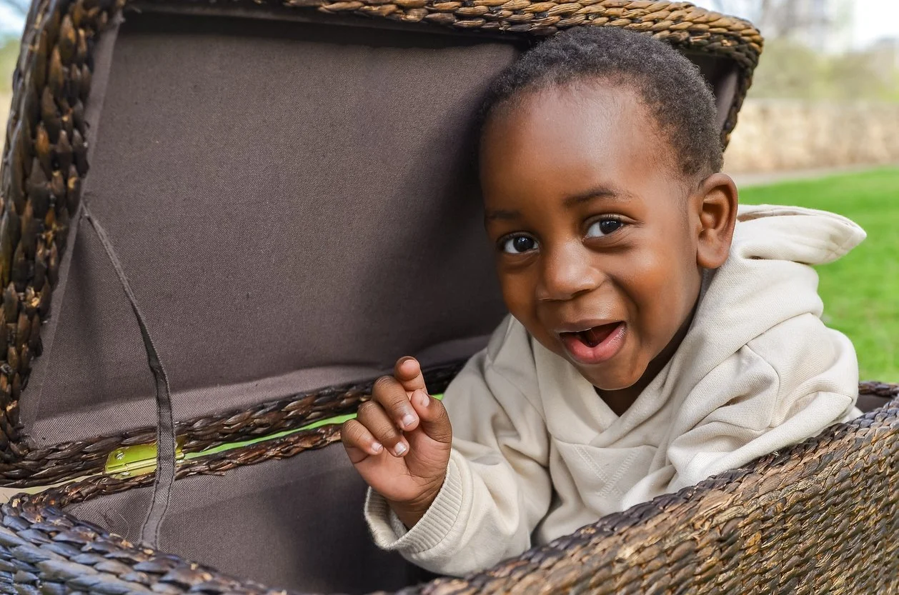 cheeky looking toddler hiding in a basket