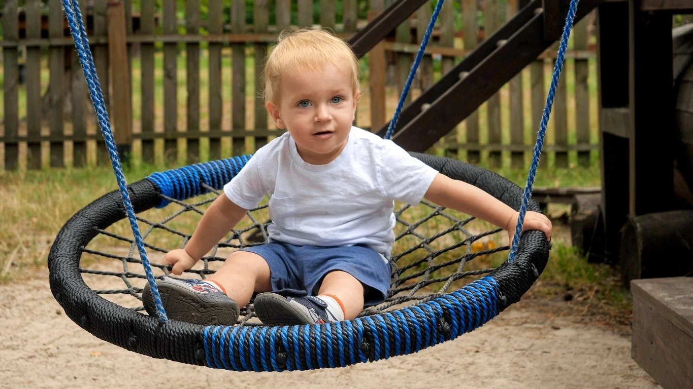 toddler boy in bucket swing