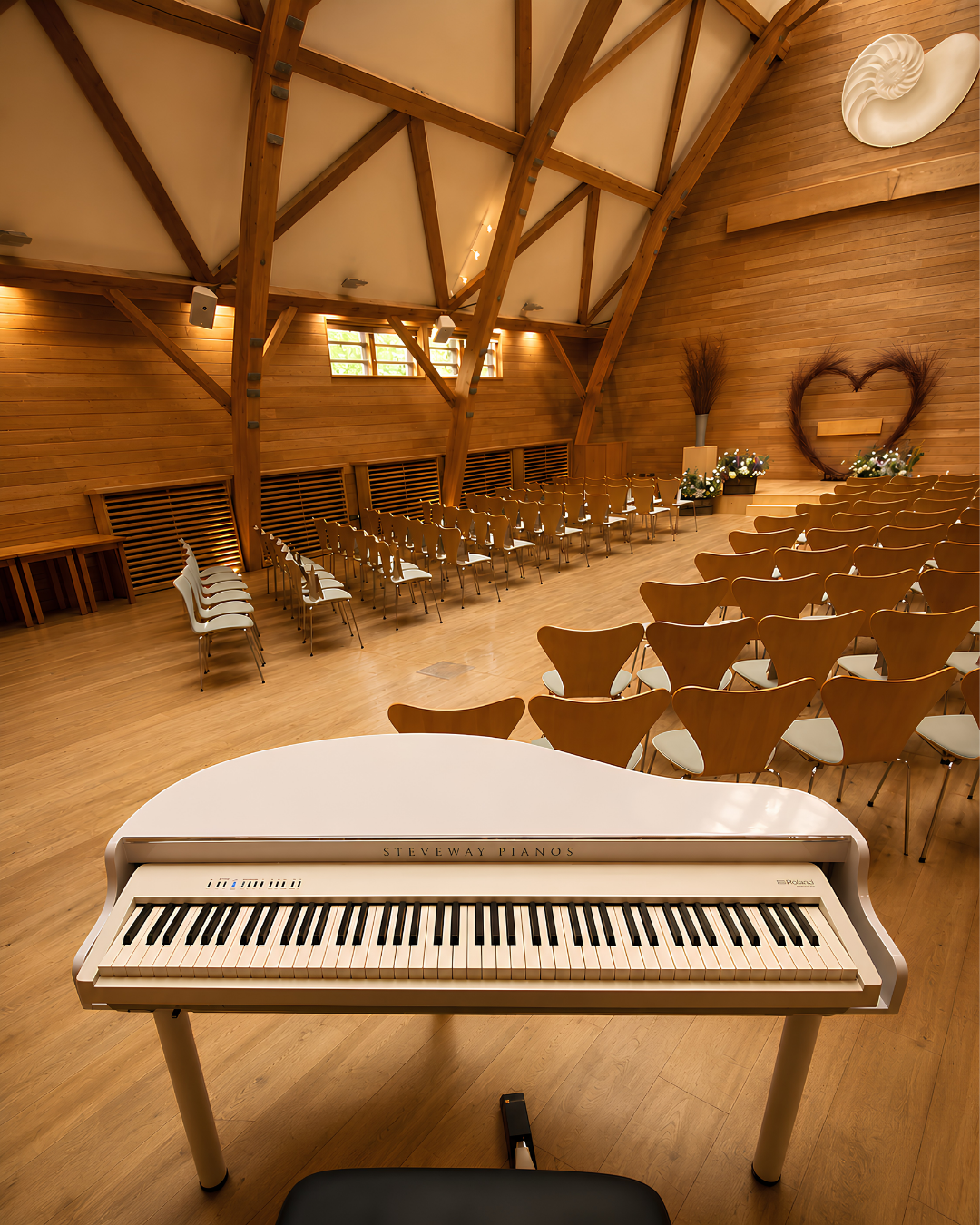 Portable white baby grand piano shell in a rustic barn wedding venue, providing elegant live piano music for ceremonies and receptions in Gloucestershire and the South West