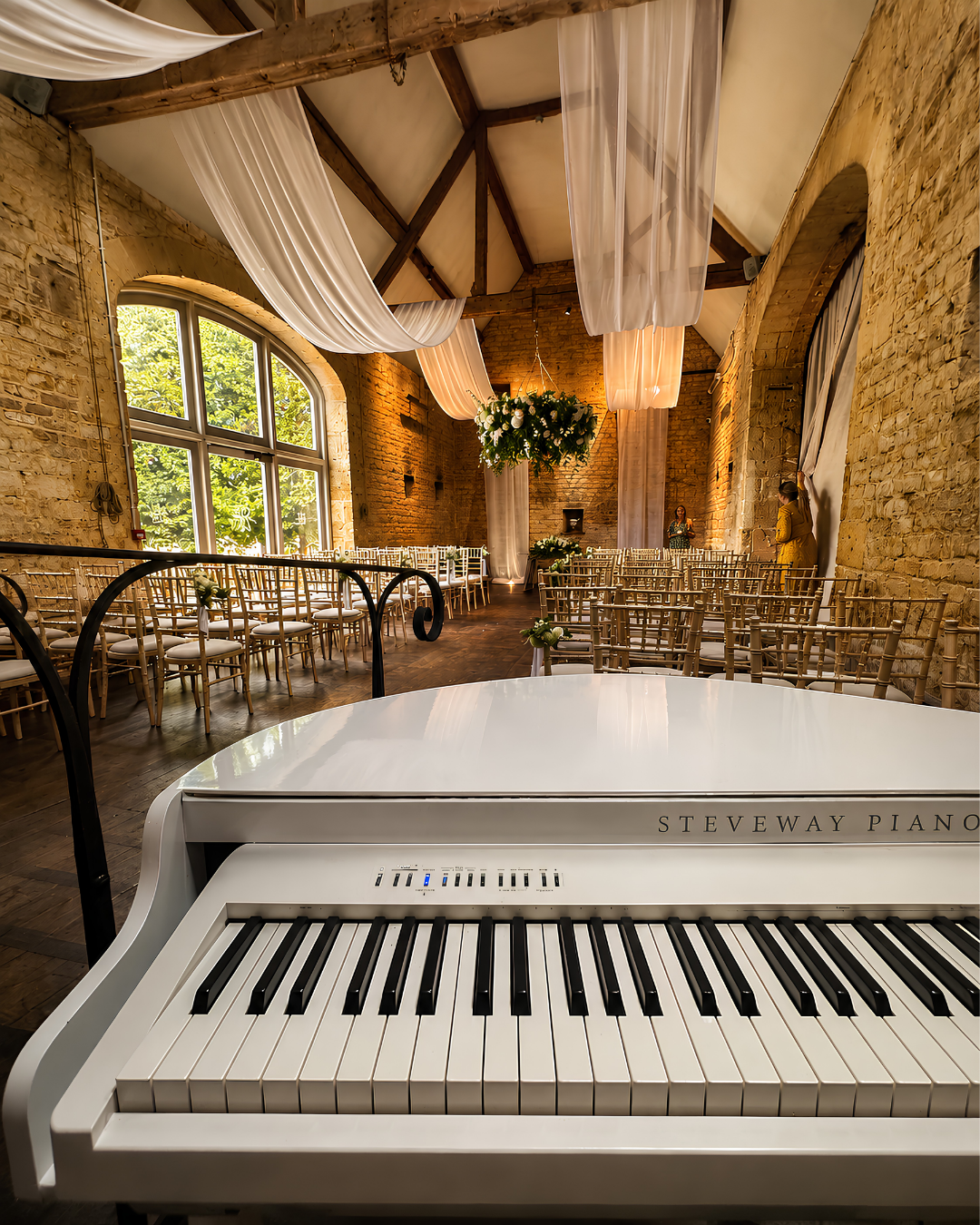 White piano shell set up in a rustic beamed barn wedding venue – wedding pianist performing in Hampshire, Berkshire and the South West