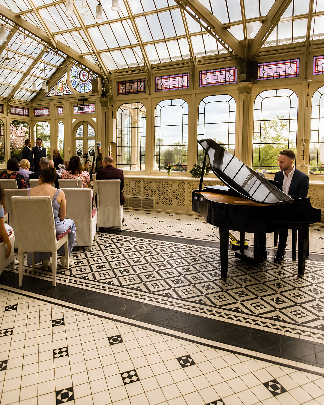 Wedding pianist performing on a grand piano in a beautiful glass conservatory during a wedding ceremony – live piano music for weddings in Bristol, Bath and Gloucestershire