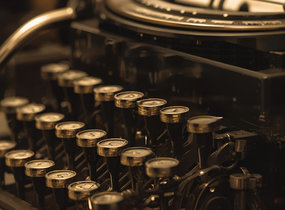 Close-up of vintage typewriter keys with round black and gold-tinted surfaces, reflecting warm light.