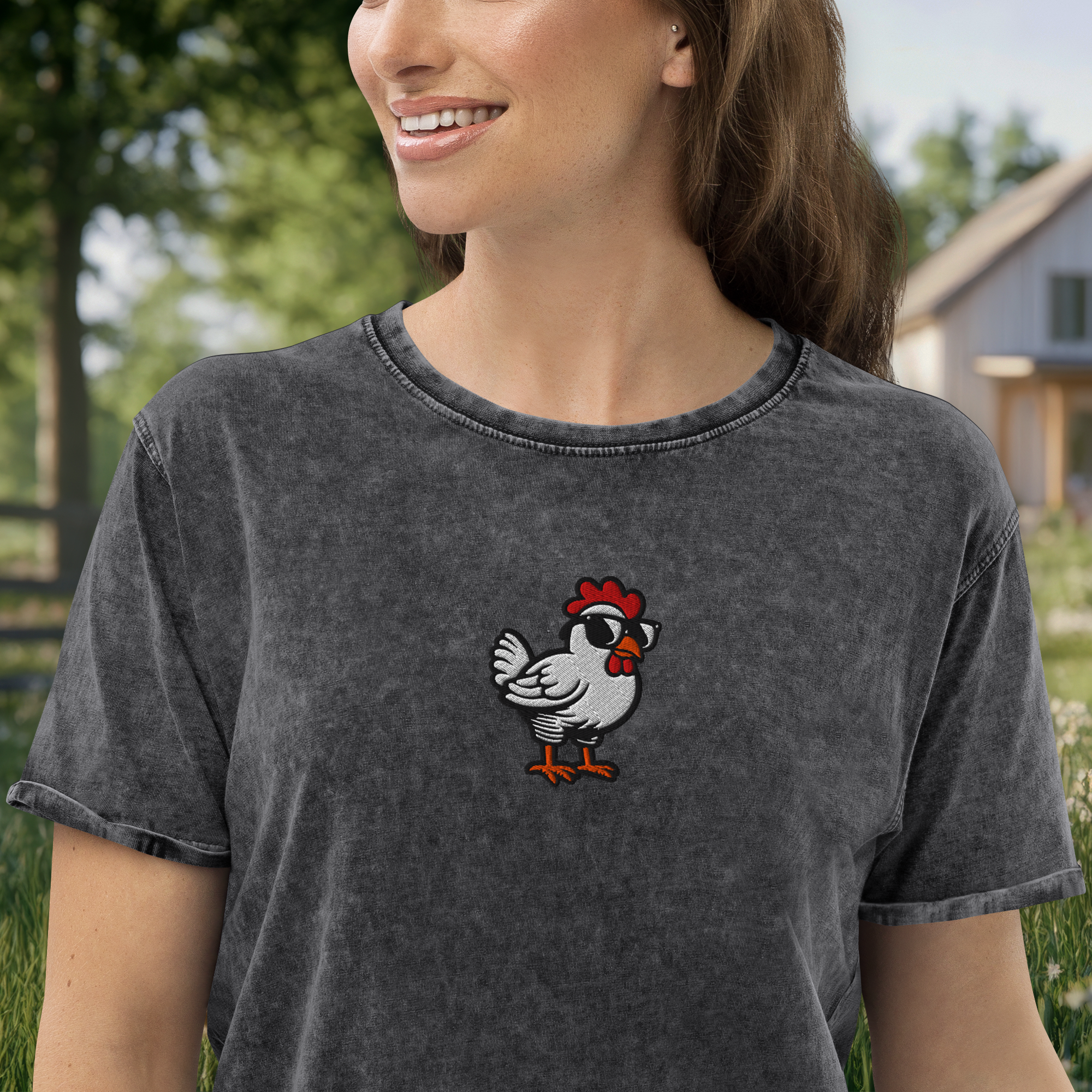 Close-up of a woman smiling outdoors, wearing a dark gray t-shirt with a cartoon chicken design on the front.