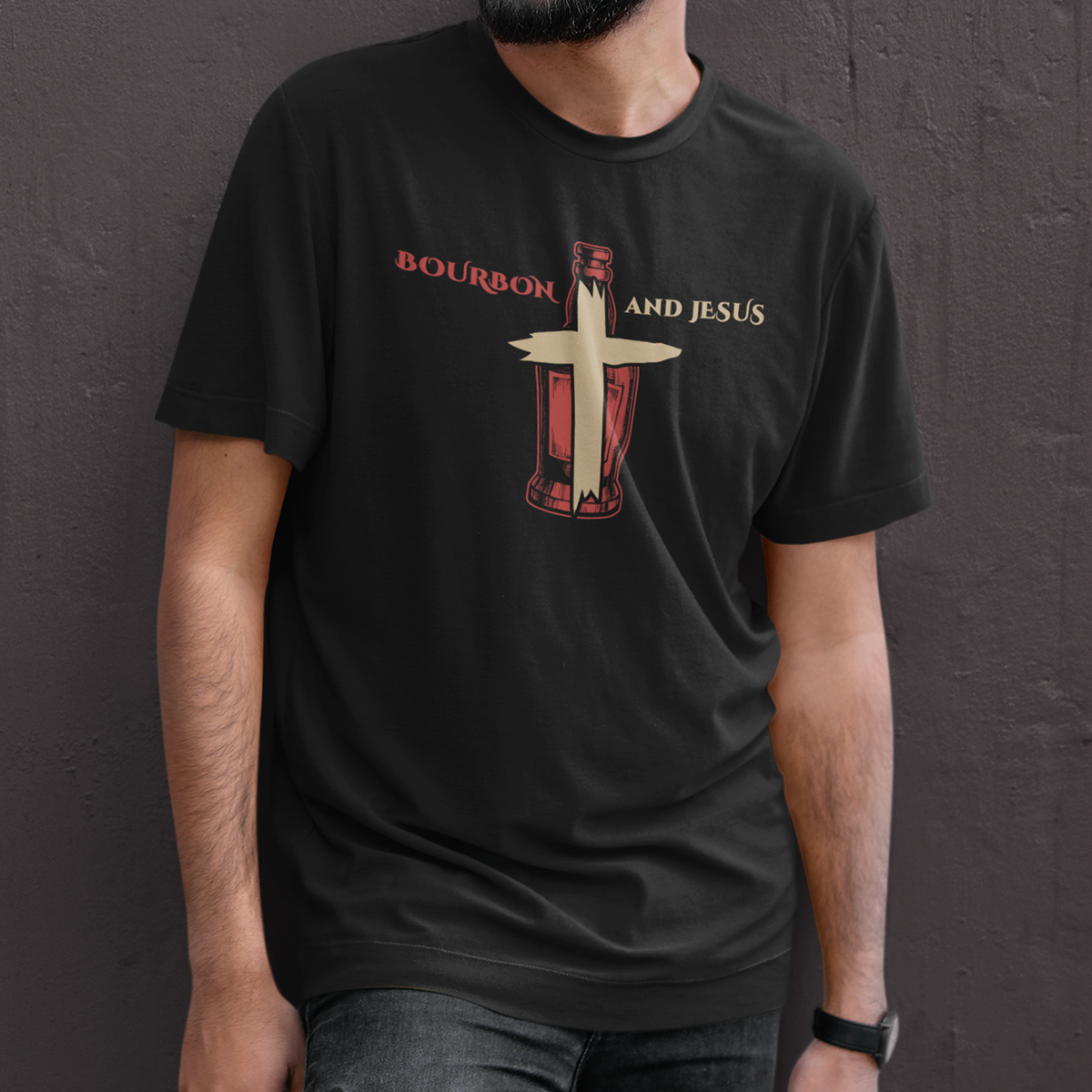 A person wearing a black t-shirt with the graphic text 'Bourbon and Jesus' and an illustration of a bourbon bottle with a cross shape on it.