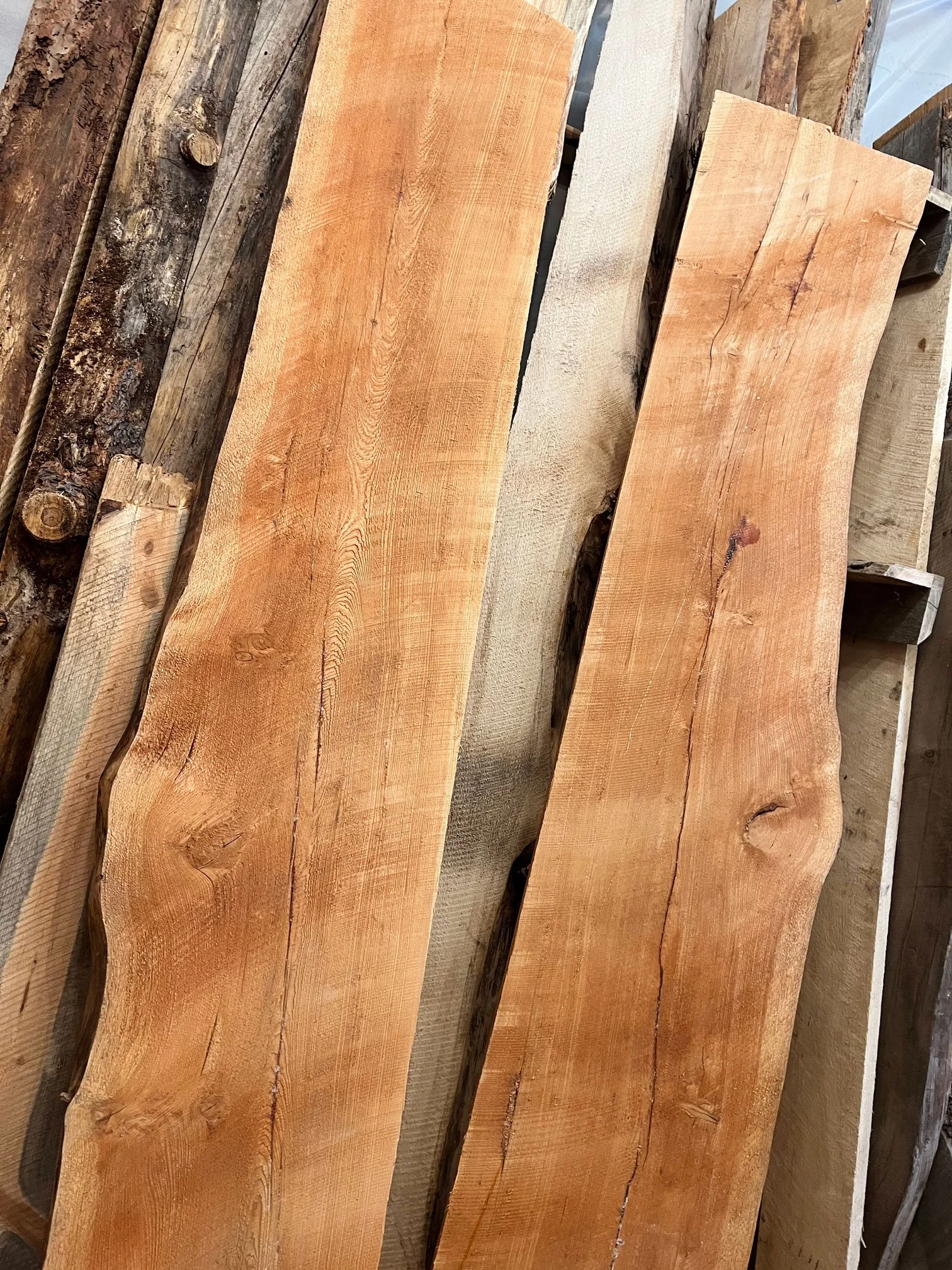 Several wooden planks, some light and some dark, stacked on each other.