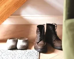 Shoes on the floor by a sofa and carpet.