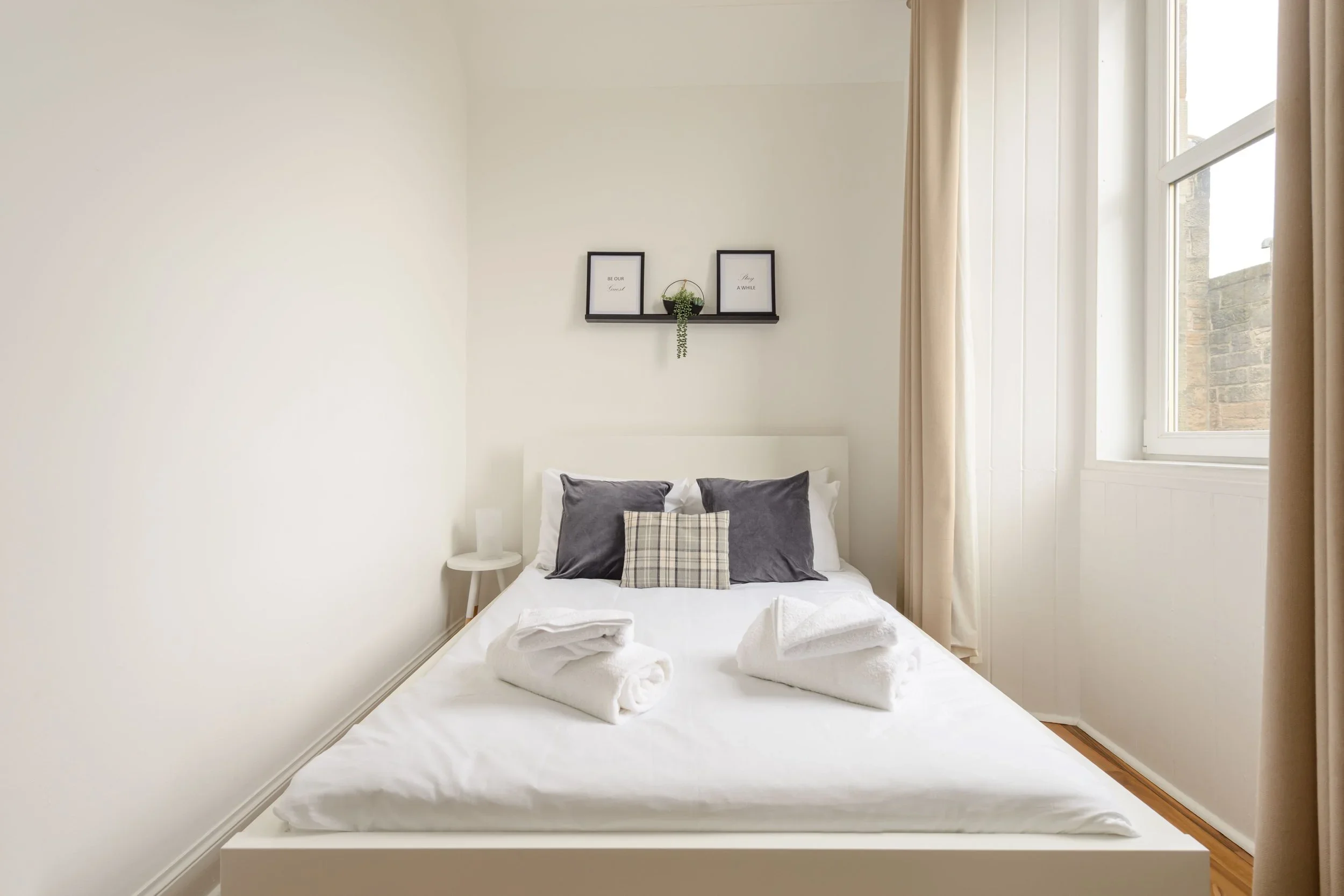 A White bed with frames above and a window to the right