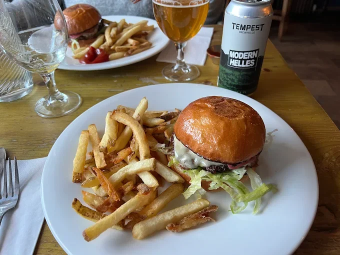 A plate with a burger and chips and a tempest drink