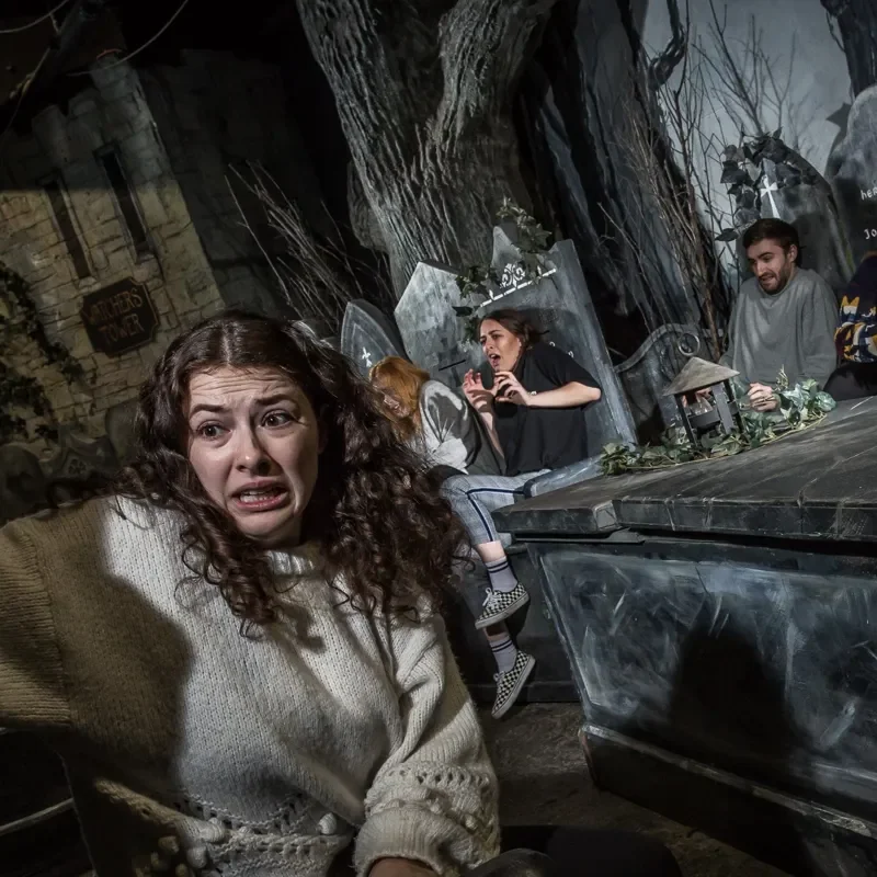 A frightened young woman with others in a graveyard.