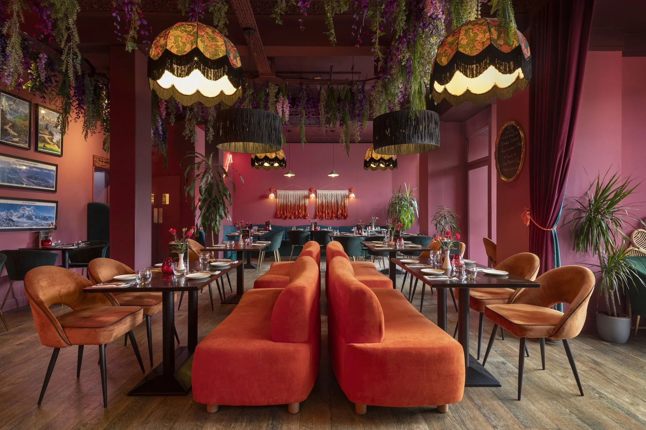 a restaurant with orange sofas and pink walls