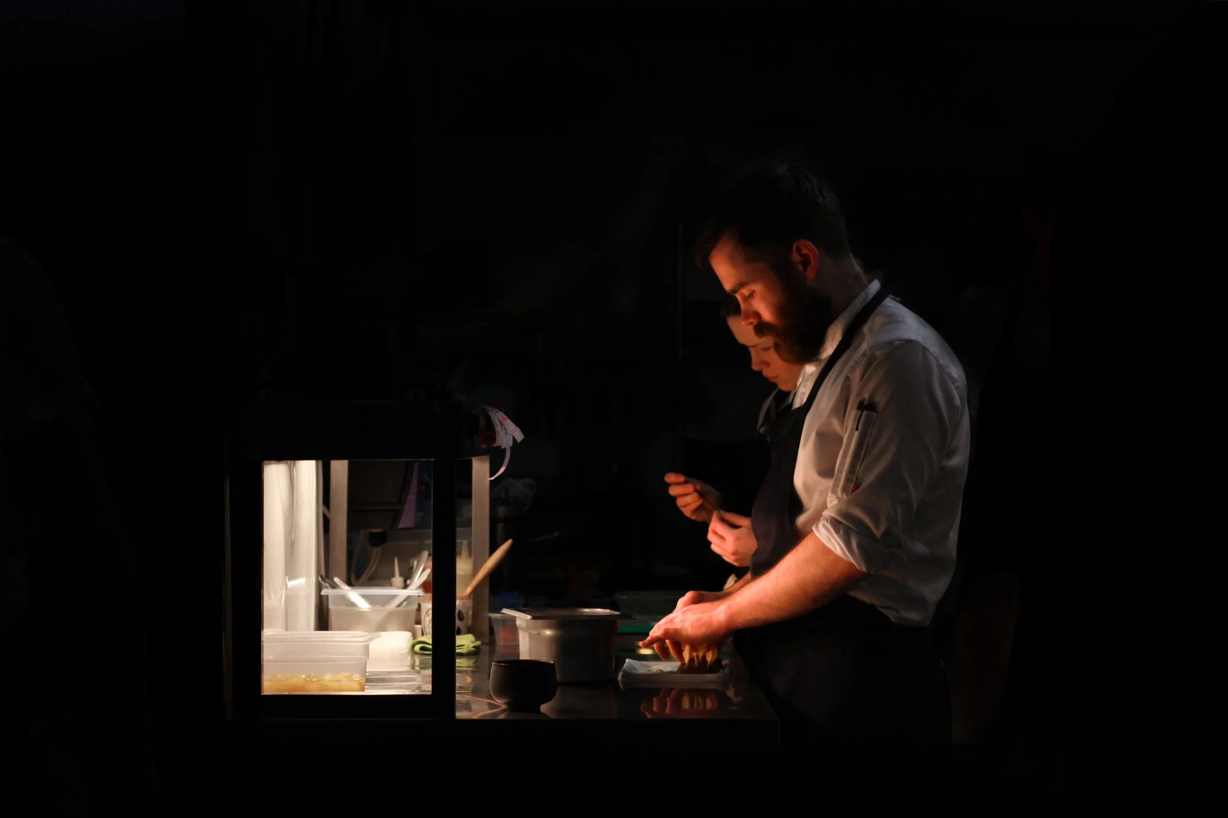 Two chefs in a dimly lit room