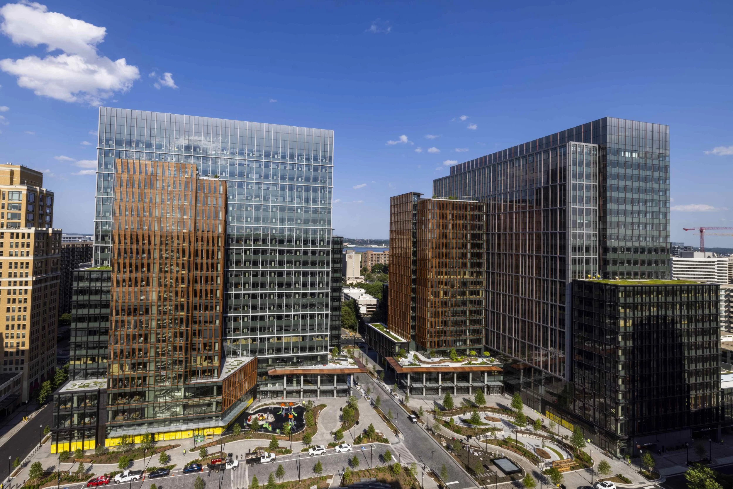 View of modern office buildings with glass facades in an urban downtown area, with clear blue sky and some scattered clouds.