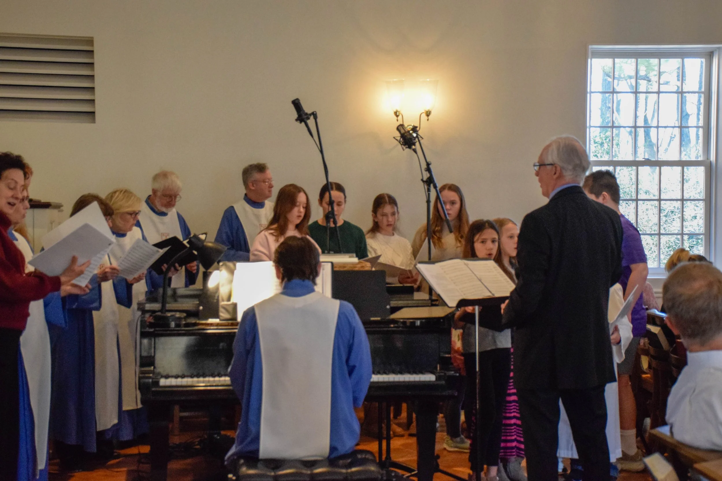 The Saint Peter's choir dressed in blue robes with white sashes singing at Saint Peters, accompanied by Jim Selway, Music Director at Saint Peter's Episcopal Church in Arlington, VA. 