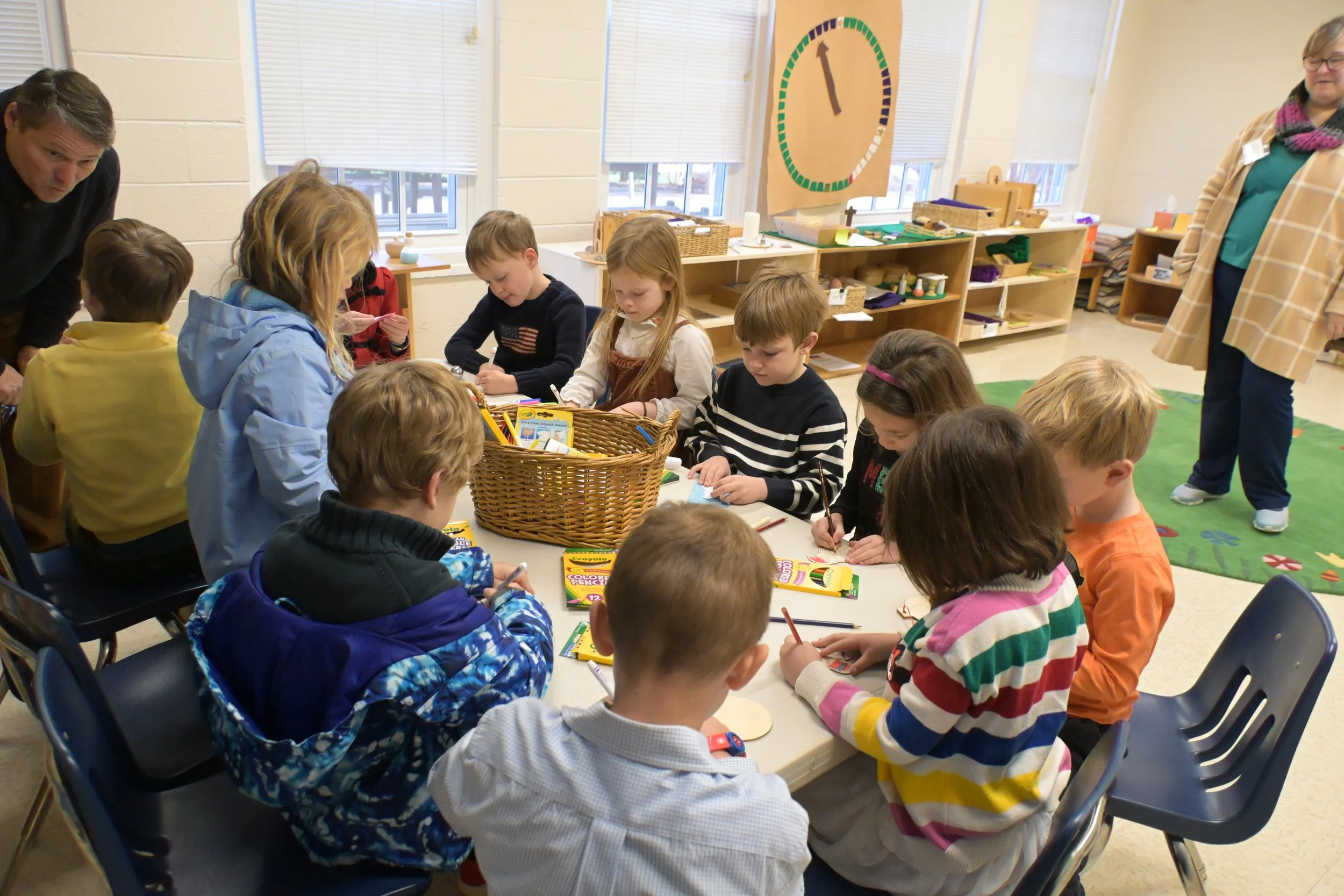 A teacher kneeling on the floor with 4-6 year old children exploring stories during Godly Play Sunday School class at Saint Peter's Episcopal Church in Arlington, VA.