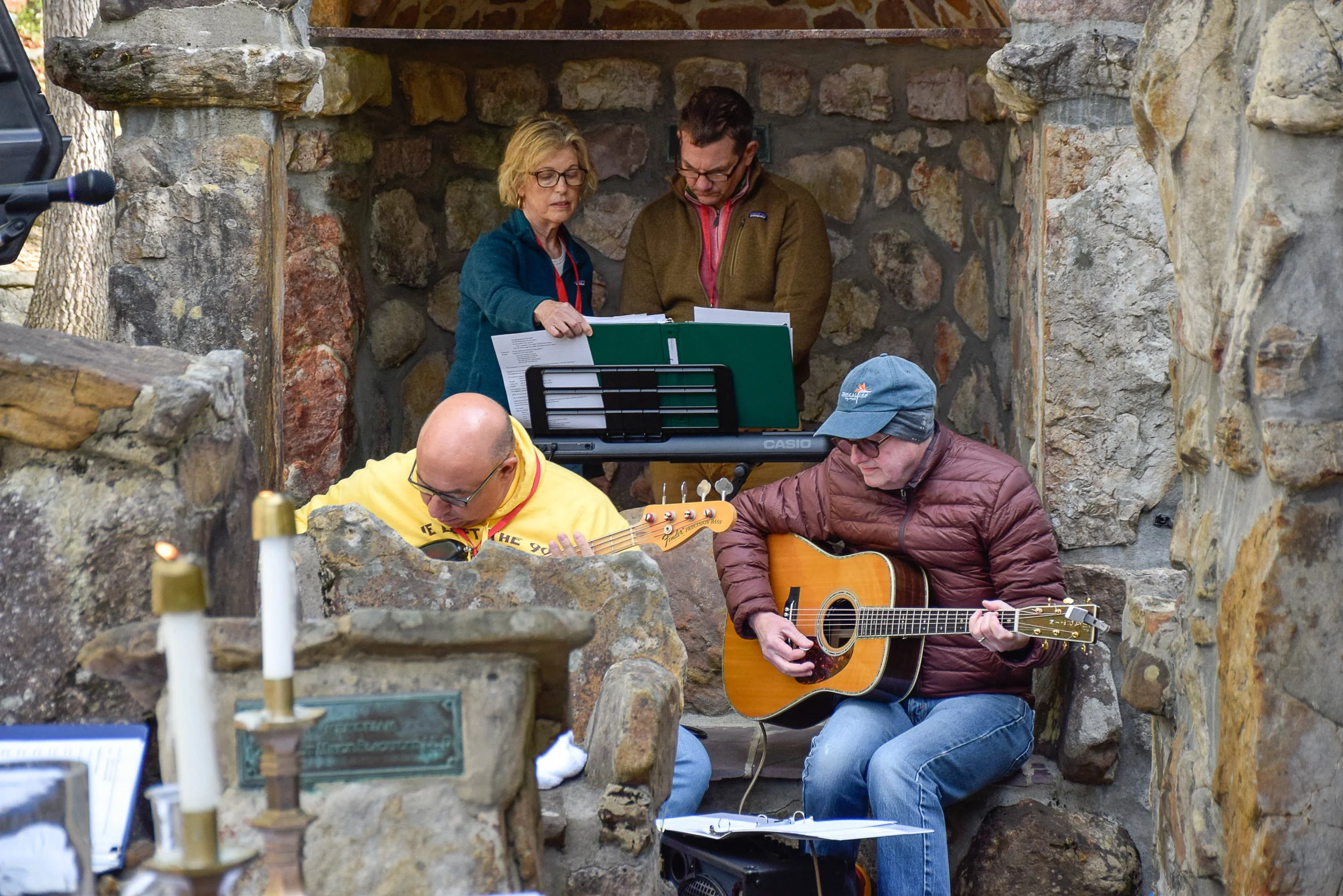 People playing instruments and singing in an outdoor chapel.