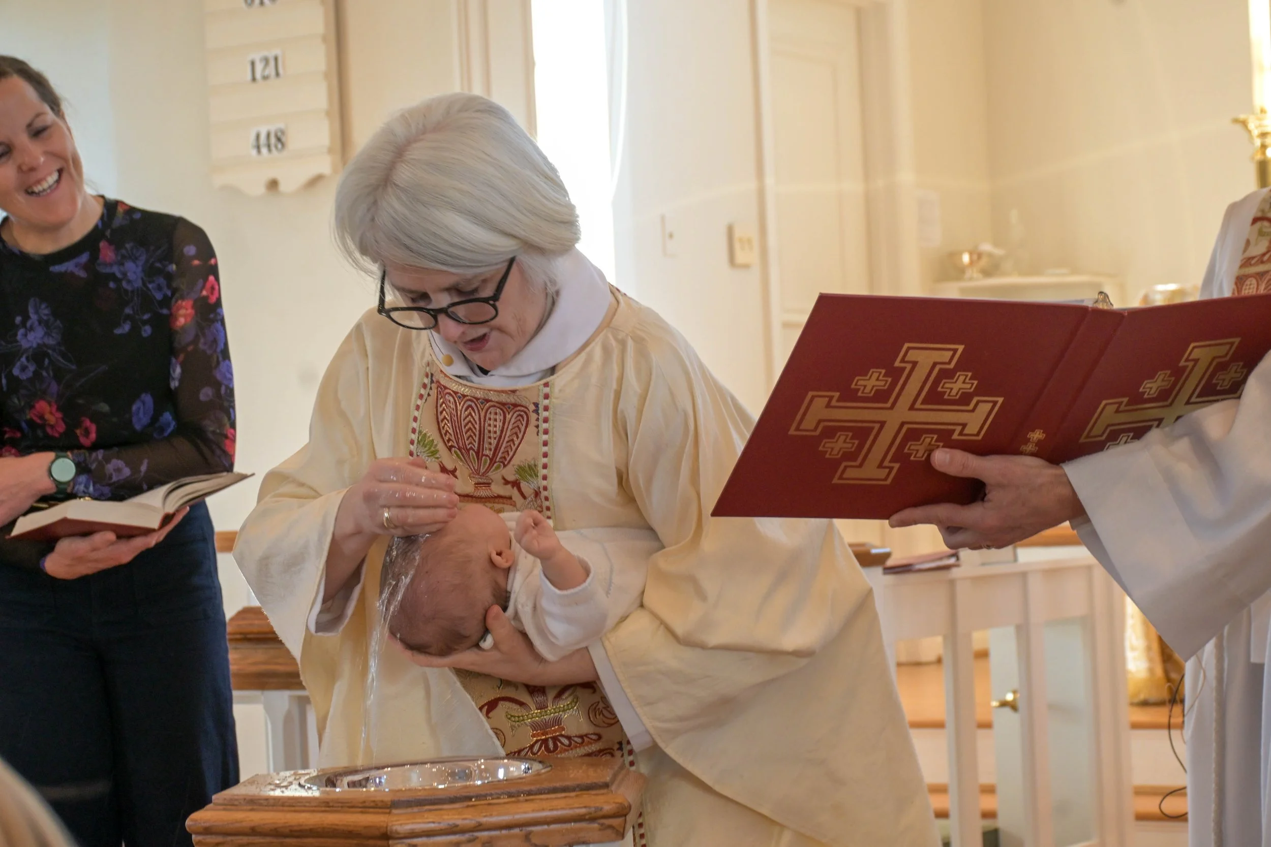 A baby being baptized by a priest.