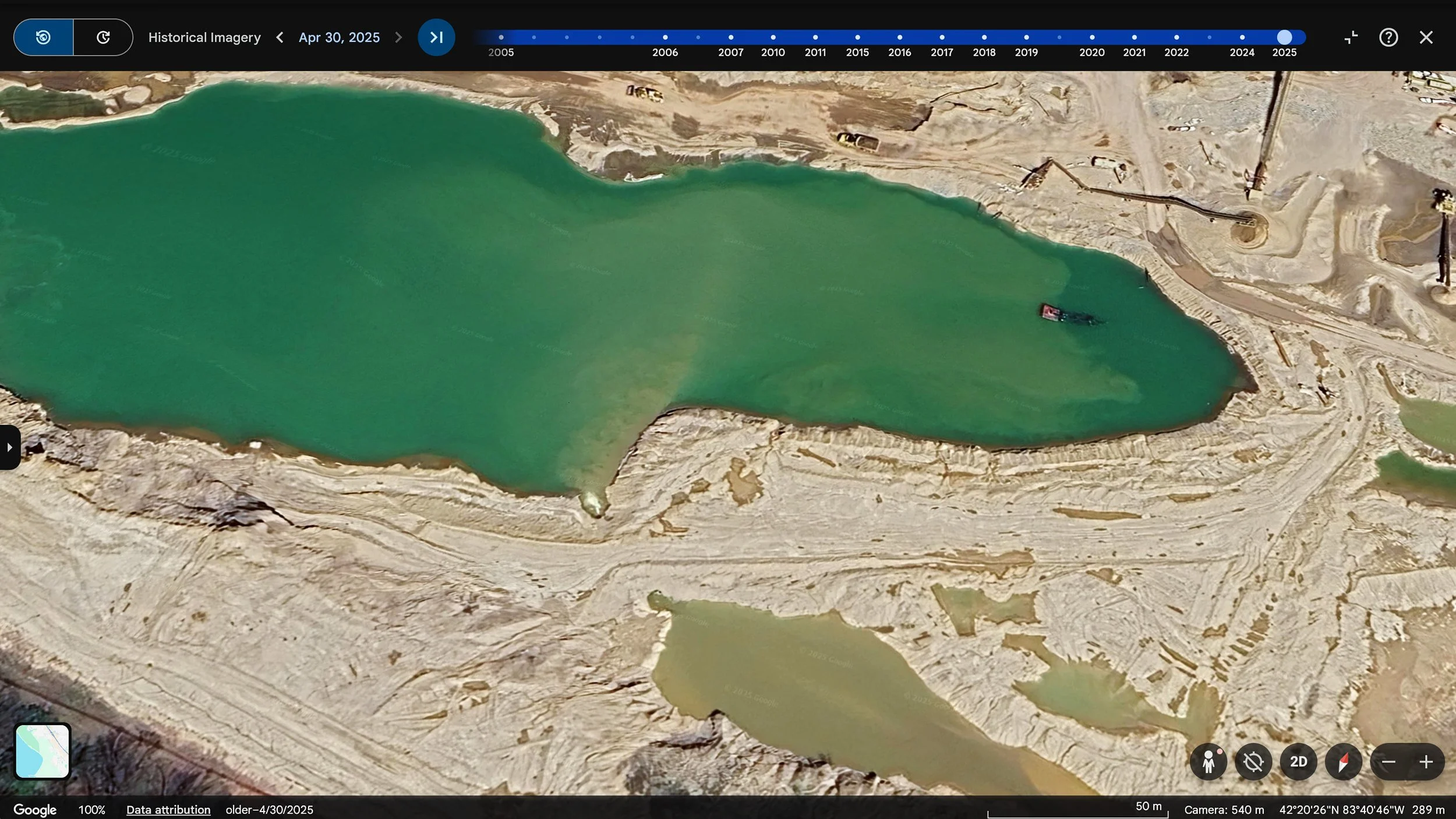 Aerial view of a construction site with a large green body of water, surrounded by dirt and land excavation equipment.