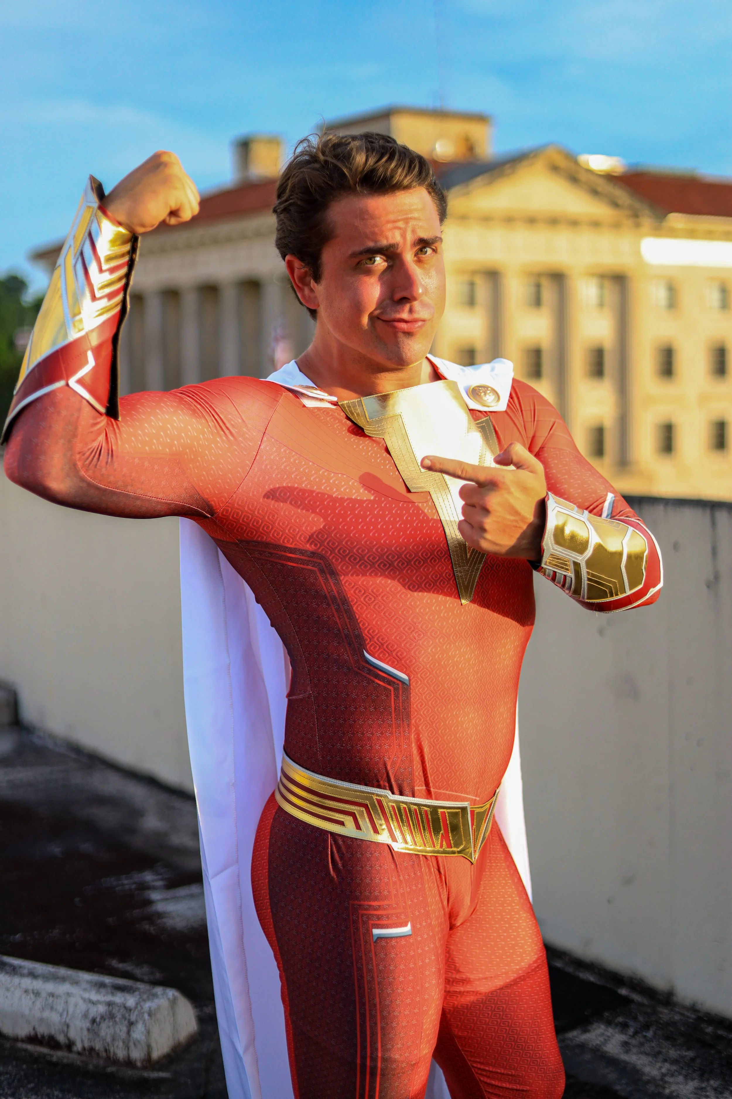 Man dressed as a superhero in a red and gold costume posing in front of a historic building