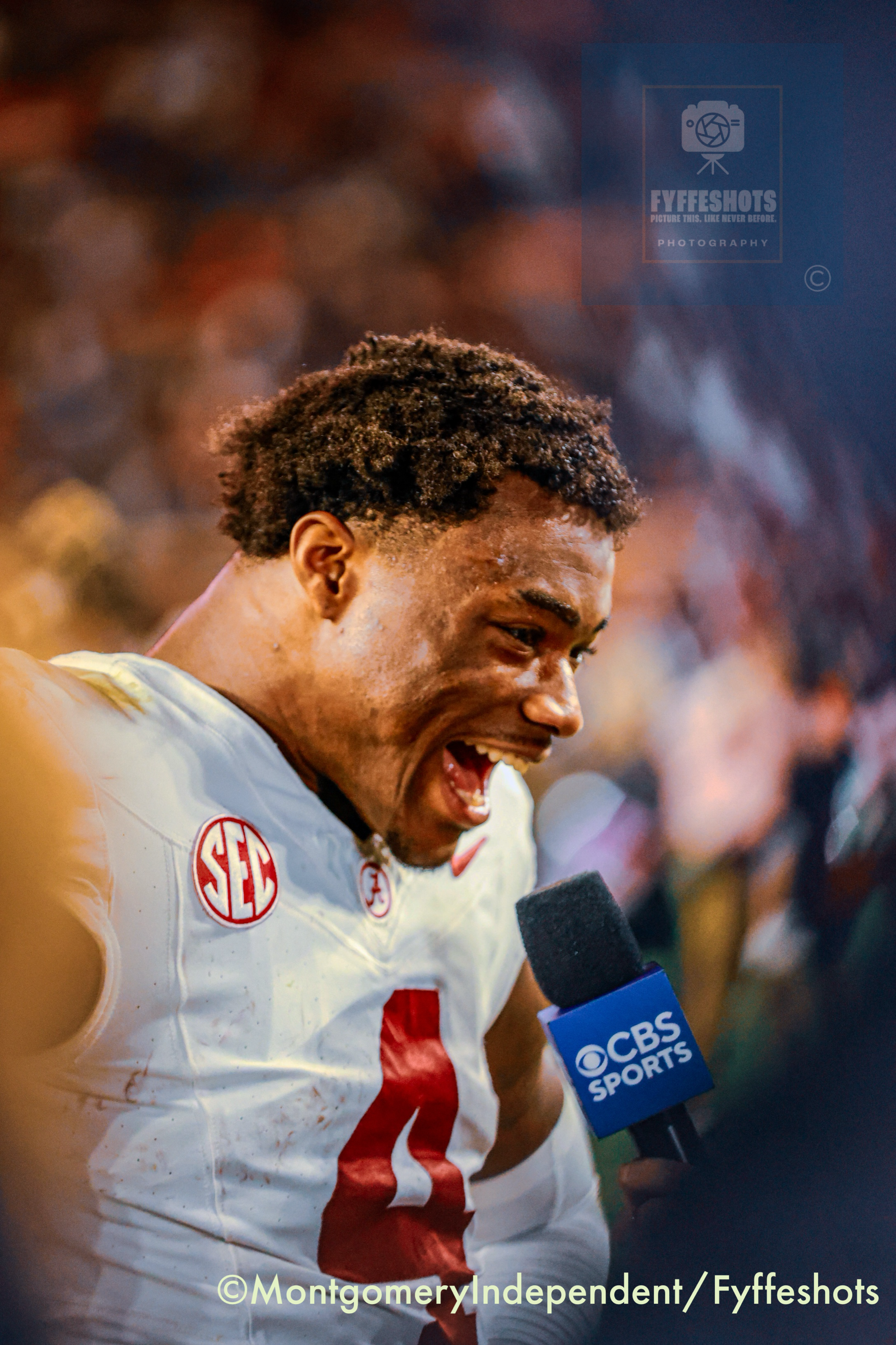 Football player in a white uniform speaking into a CBS Sports microphone after a game.