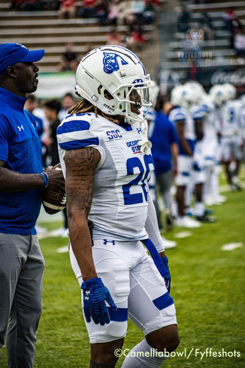 Georgia State football player in white and blue uniform and helmet standing on the sideline during a game