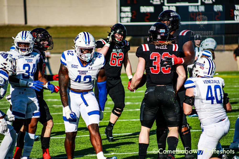 Georgia State Panthers and Ball State Cardinals football players competing on the field