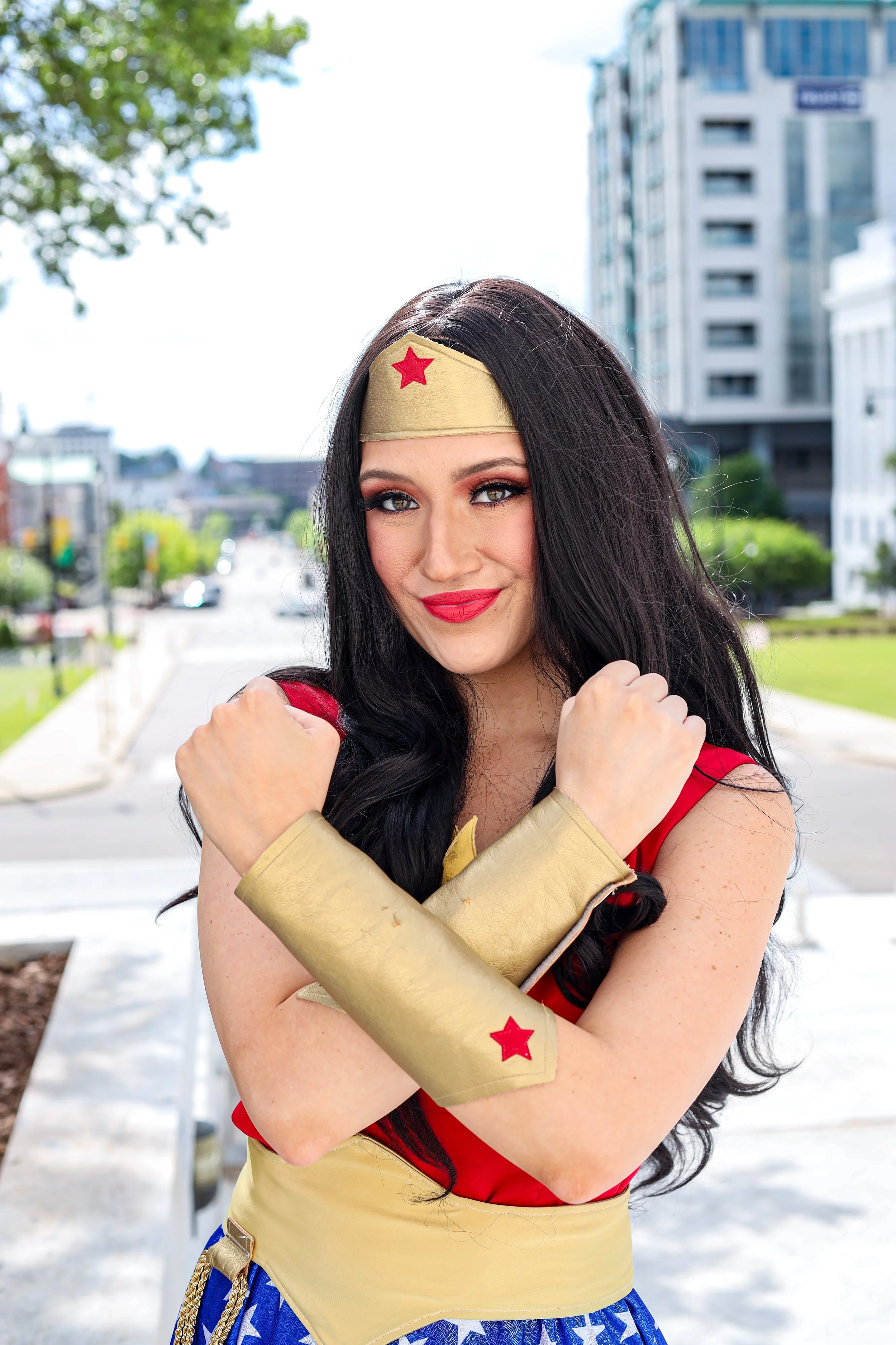 Woman dressed as Wonder Woman posing outdoors in front of a city building