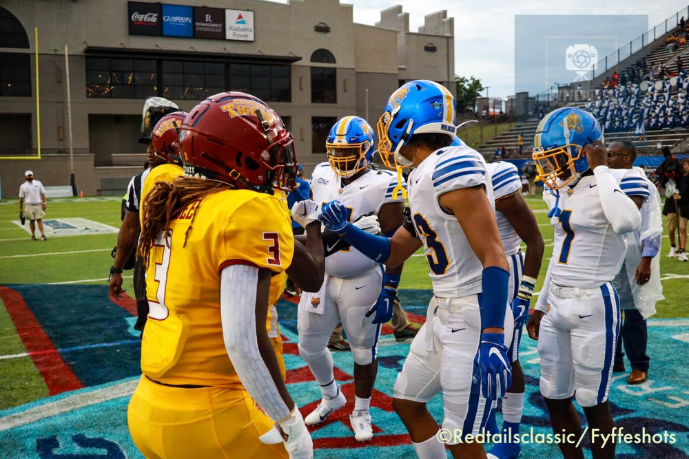 College football players from opposing teams meet on the field before a game.