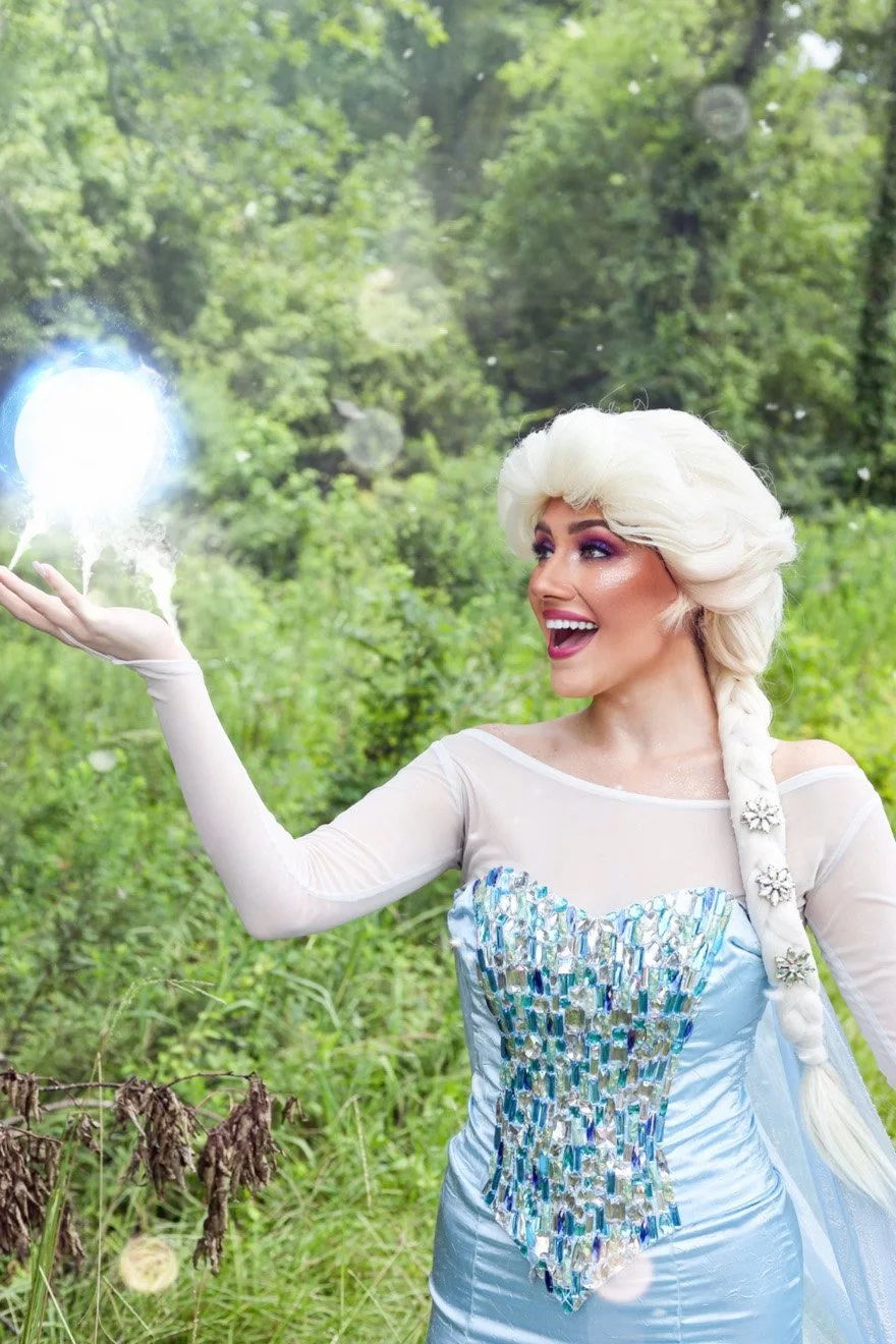 Woman in an Elsa-inspired costume holding a glowing orb outdoors