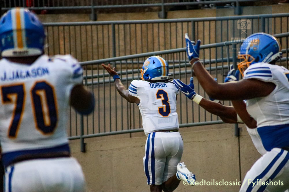 Football players in blue-and-white uniforms celebrate near the sideline during a game.