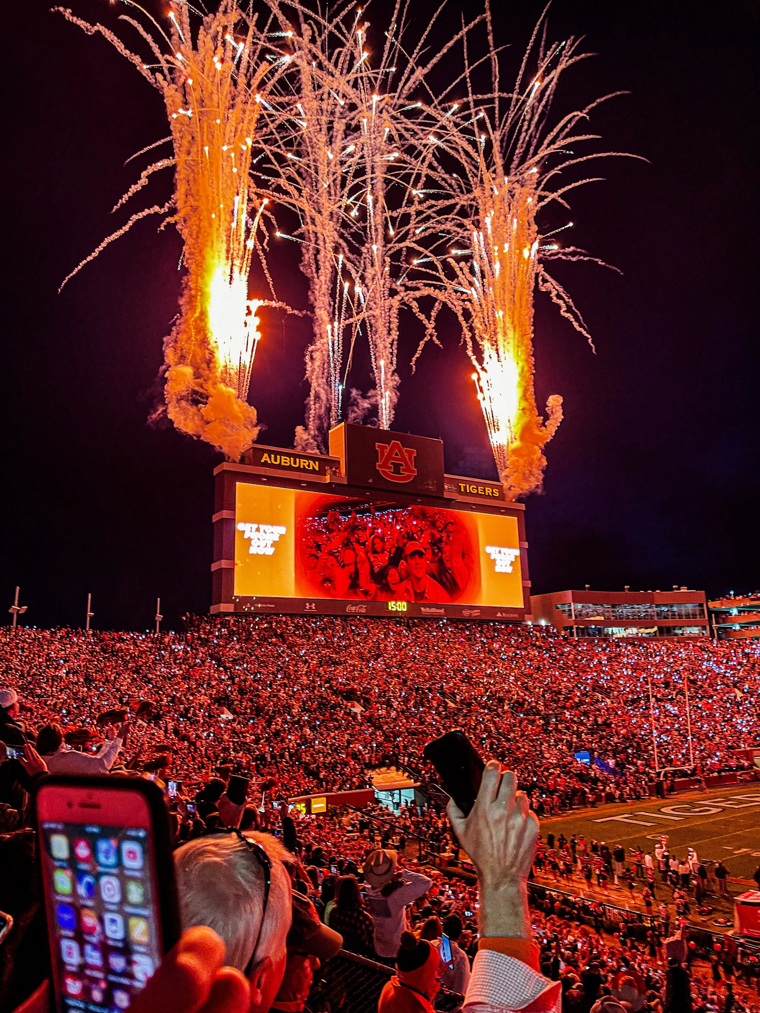 Auburn Tigers fans celebrate beneath fireworks at Jordan-Hare Stadium during a nighttime football game.